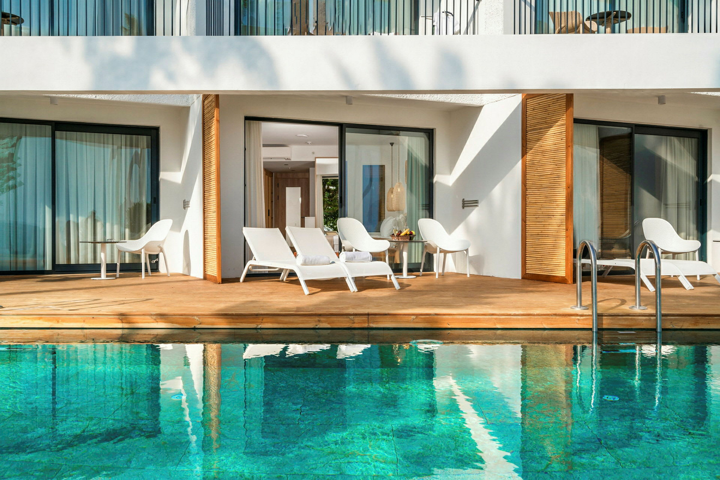 Terrasse ved pool med liggestole og bord. (AI-genereret tekst)