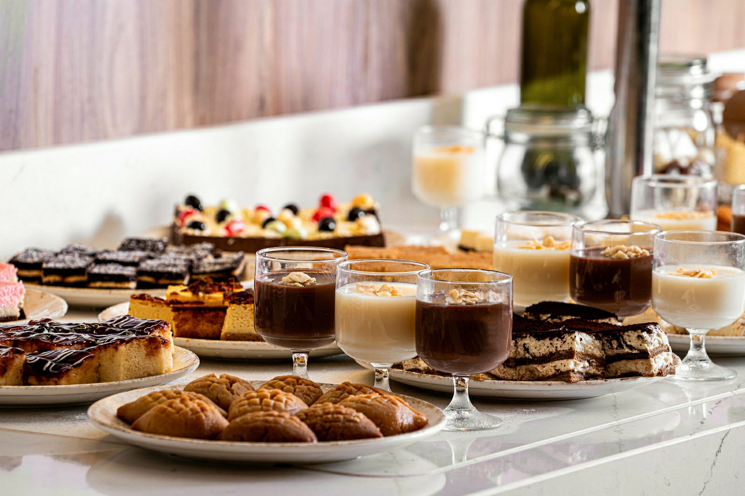 Et bord med forskellige desserter, inklusive glas med mousse og bagværk. (AI-genereret tekst)