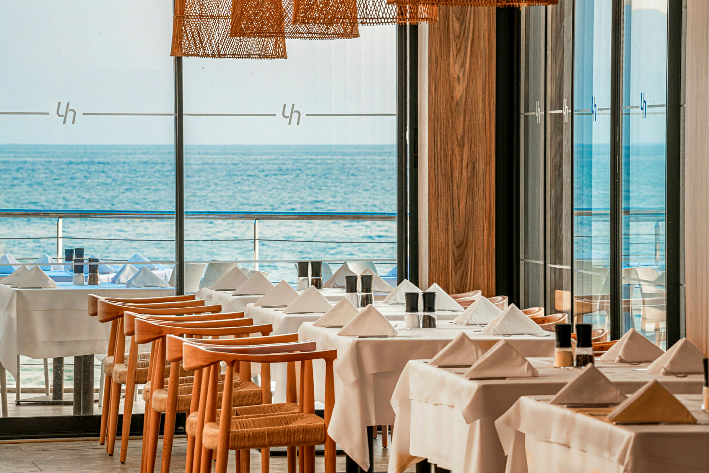Et restaurantområde med dækkede borde og udsigt over havet. (AI-genereret tekst)