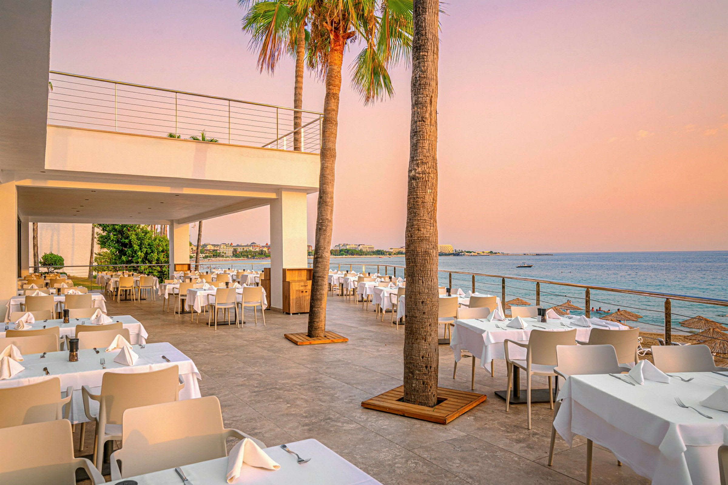 Udendørs restaurant med havudsigt ved solnedgangen. (AI-genereret tekst)