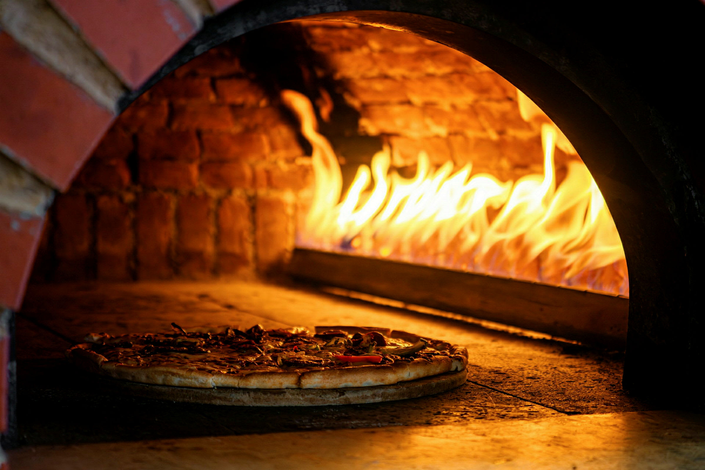 Brændefyret ovn med en pizza, der bages. (AI-genereret tekst)
