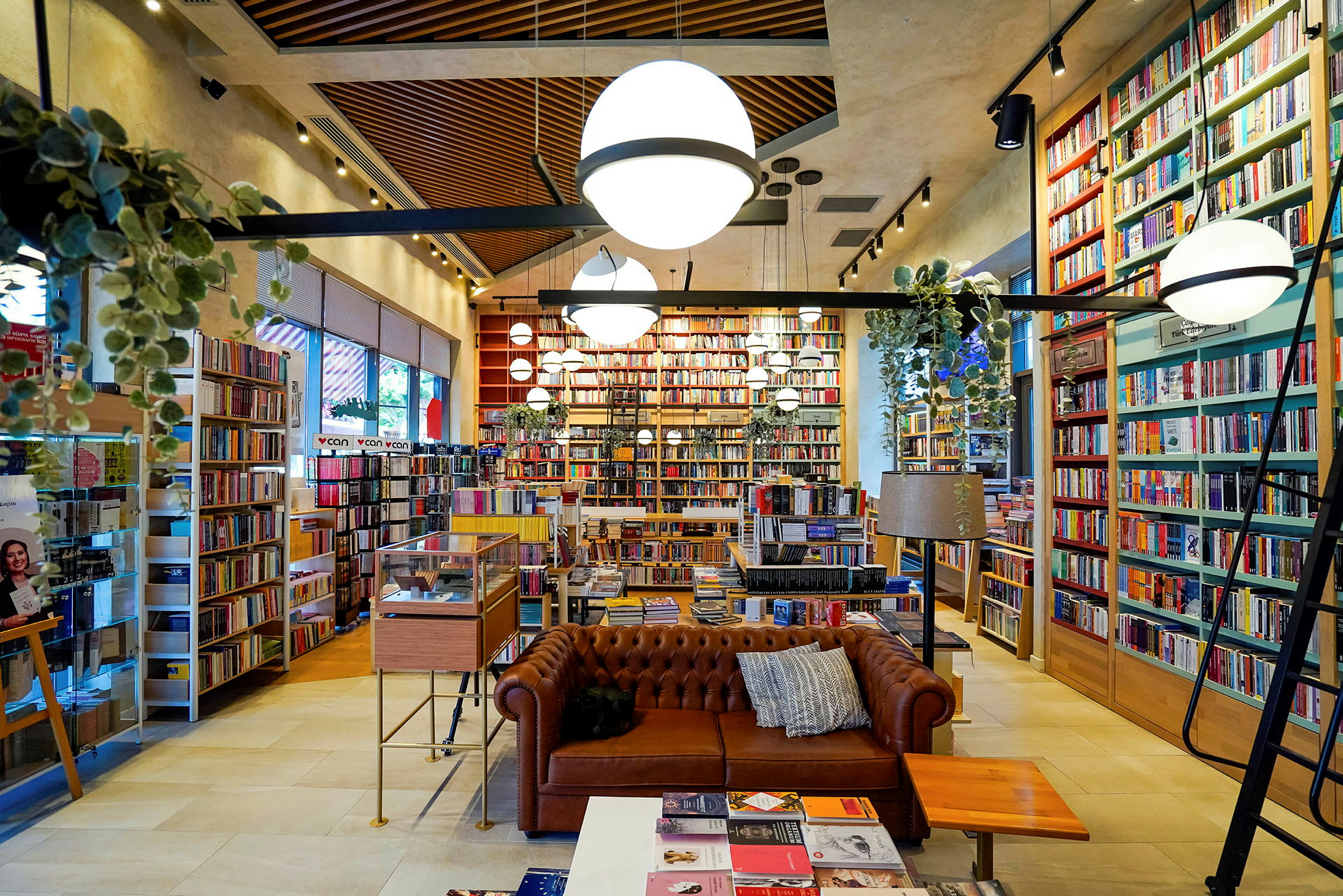 Et velorganiseret bibliotek eller boghandel med en brun sofa og mange reoler fyldt med bøger. (AI-genereret tekst)