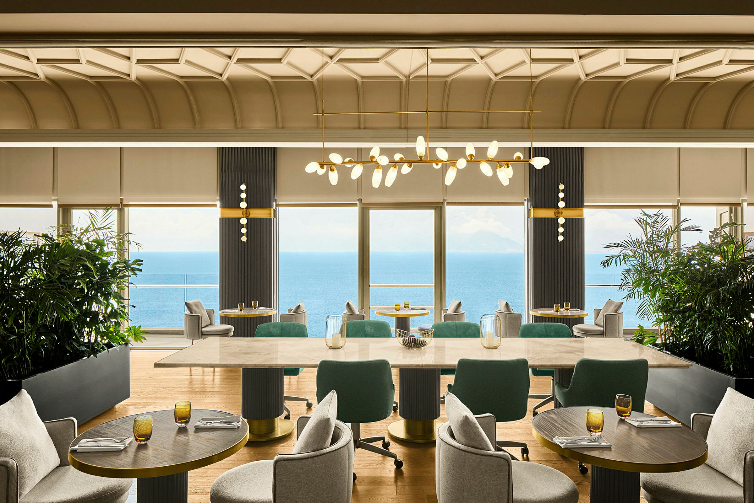 Et veludstyret restaurantområde med store vinduer, der tilbyder udsigt over havet. (AI-genereret tekst)