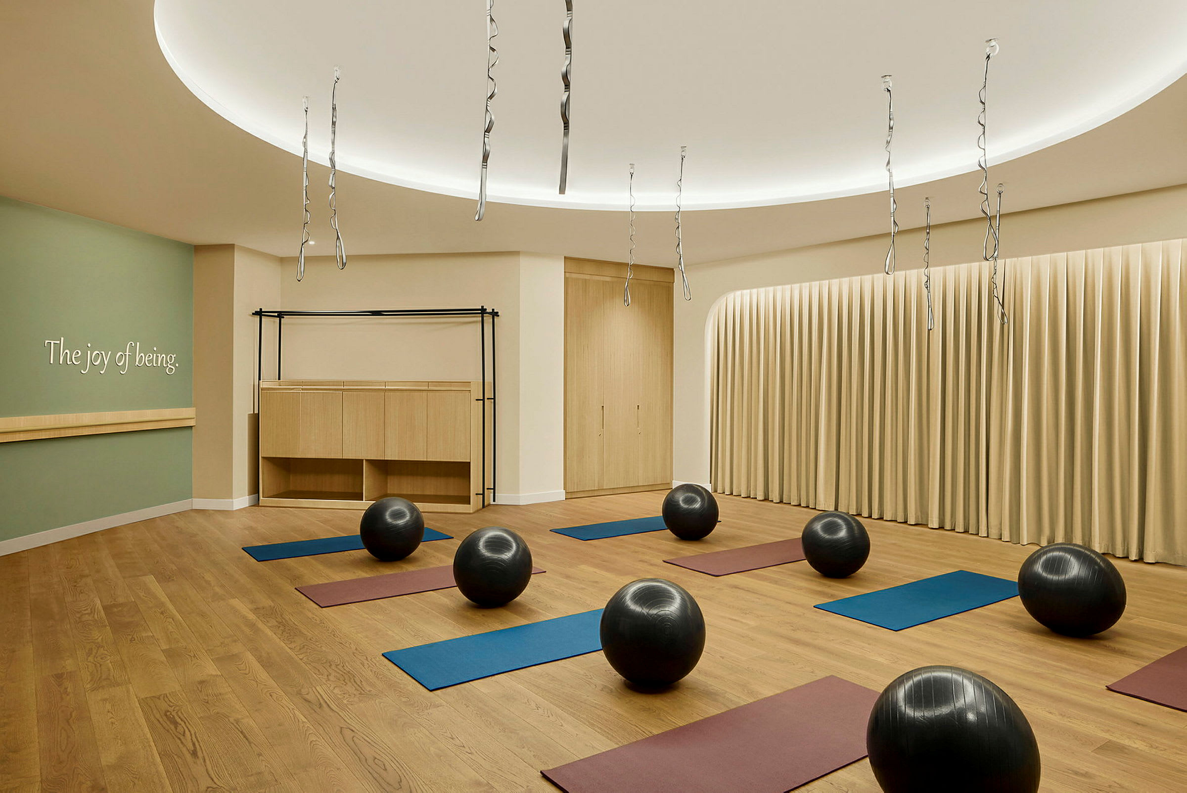 Et yoga- eller træningsrum med træningsmåtter og balancebolde jævnt fordelt på et trægulv. (AI-genereret tekst)