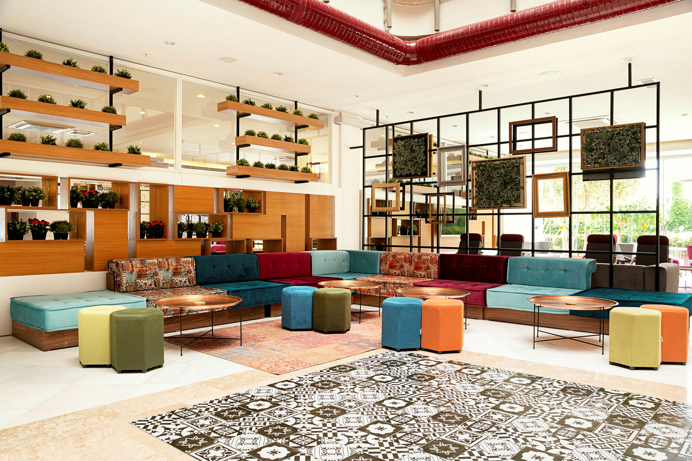 Billede af en stilfuldt indrettet lounge med farverige sofaer, siddepuffer og vægdekorationer. (AI-genereret tekst)