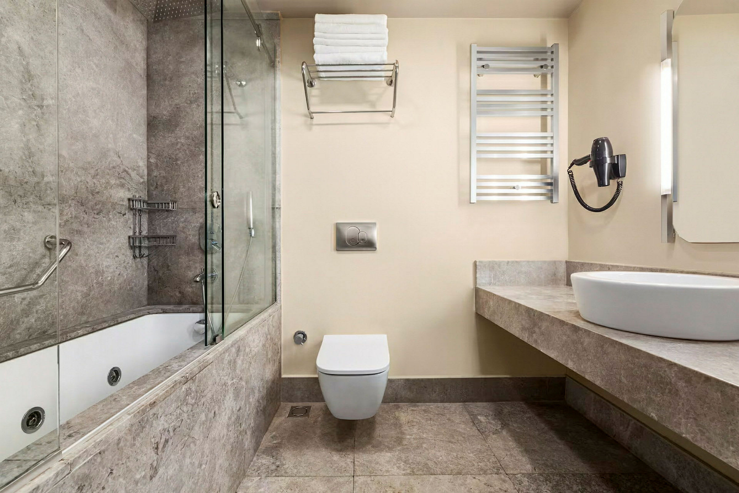 Et badeværelse med moderne indretning, herunder en brusekabine i glas, toilet, håndvask på stenbordplade og håndklædeholder på væggen. (AI-genereret tekst)