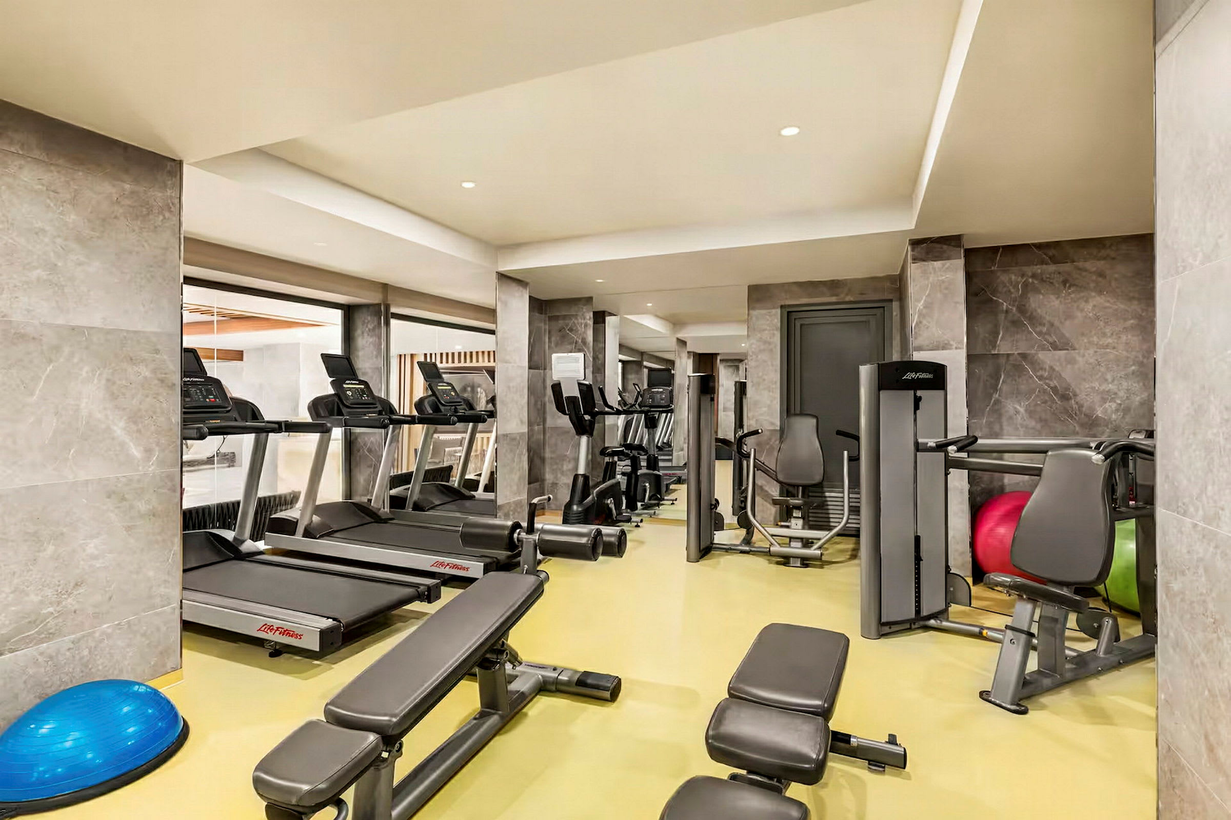 Billede af et fitnesscenter med træningsmaskiner og udstyr, herunder løbebånd og styrketræningsbænke. (AI-genereret tekst)