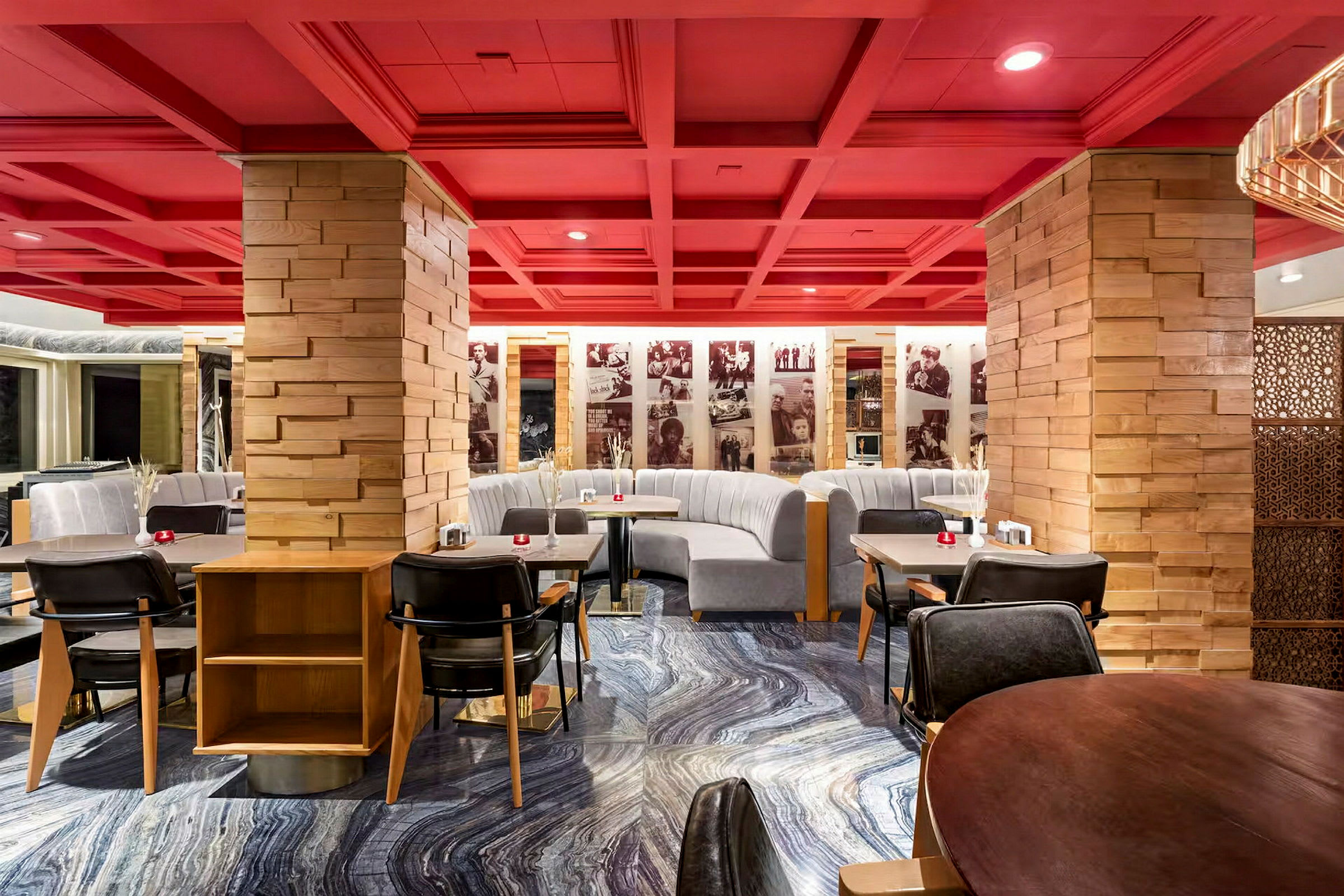 En restaurant med røde lofter og træstolper samt grå sofaer og moderne spiseborde. (AI-genereret tekst)