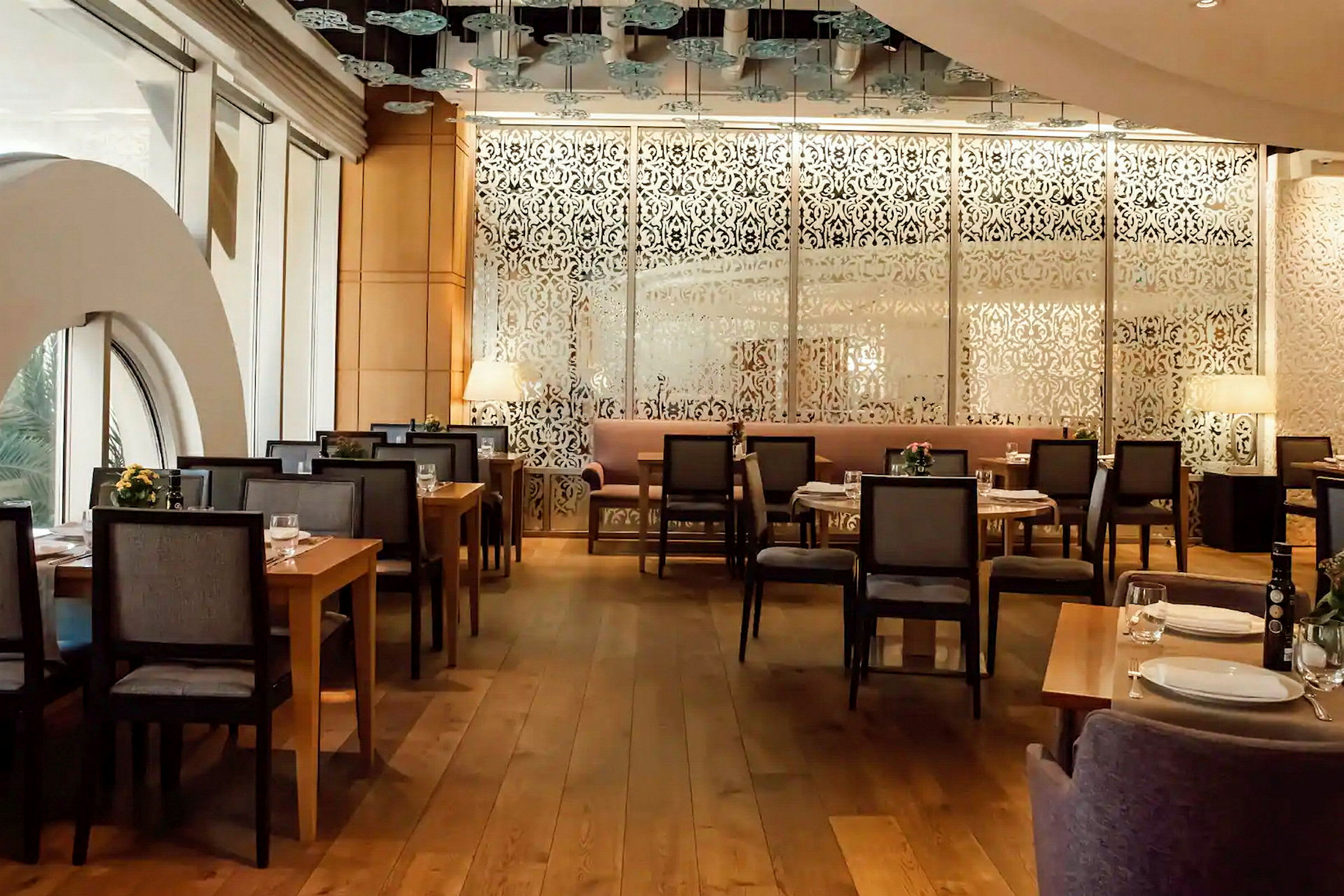 En elegant restaurant med dekorative mønstrede skærme og træborde omgivet af stole. (AI-genereret tekst)