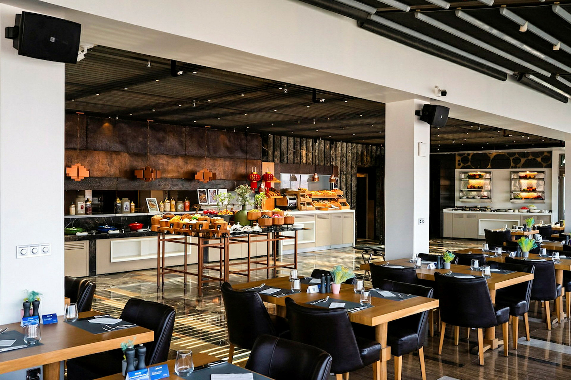 En restaurant med opstillede borde og stole samt en buffetskranke fyldt med mad og drikke. (AI-genereret tekst)