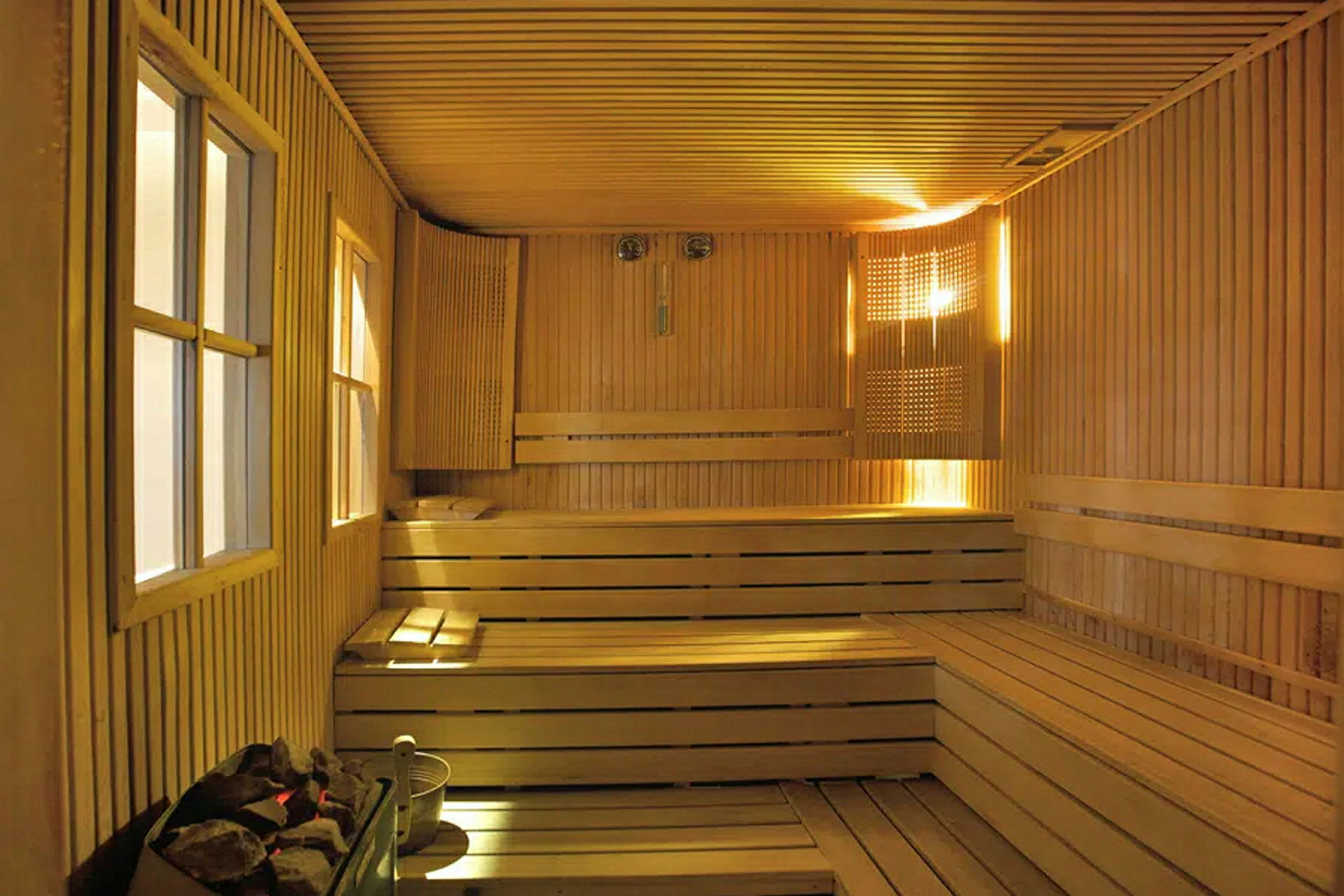 Billede af en sauna med træpaneler, bænke og en varmeenhed i forgrunden. (AI-genereret tekst)