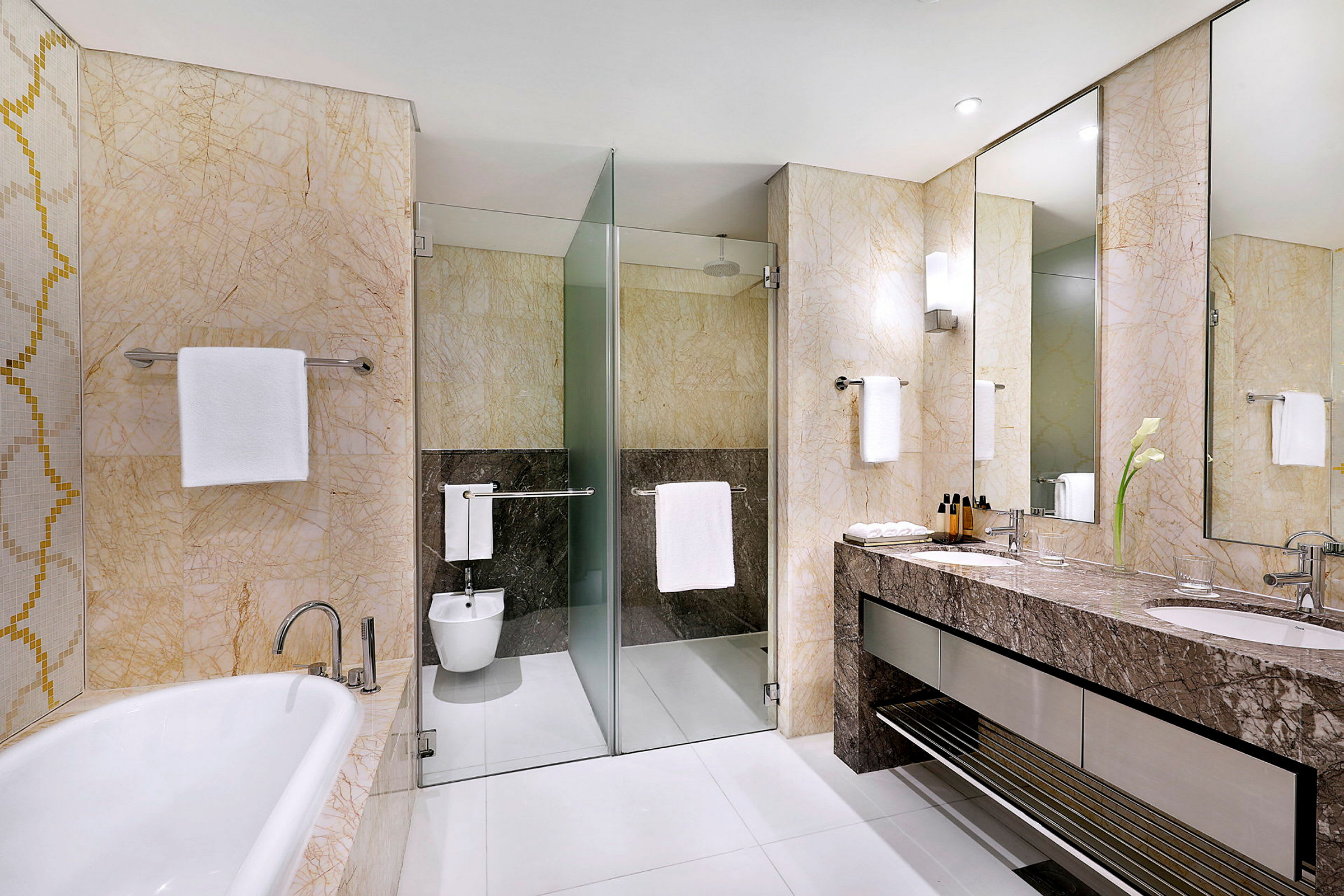 Et moderne badeværelse med badekar, bruser med glasvæg, bidet og håndvask med spejle. (AI-genereret tekst)