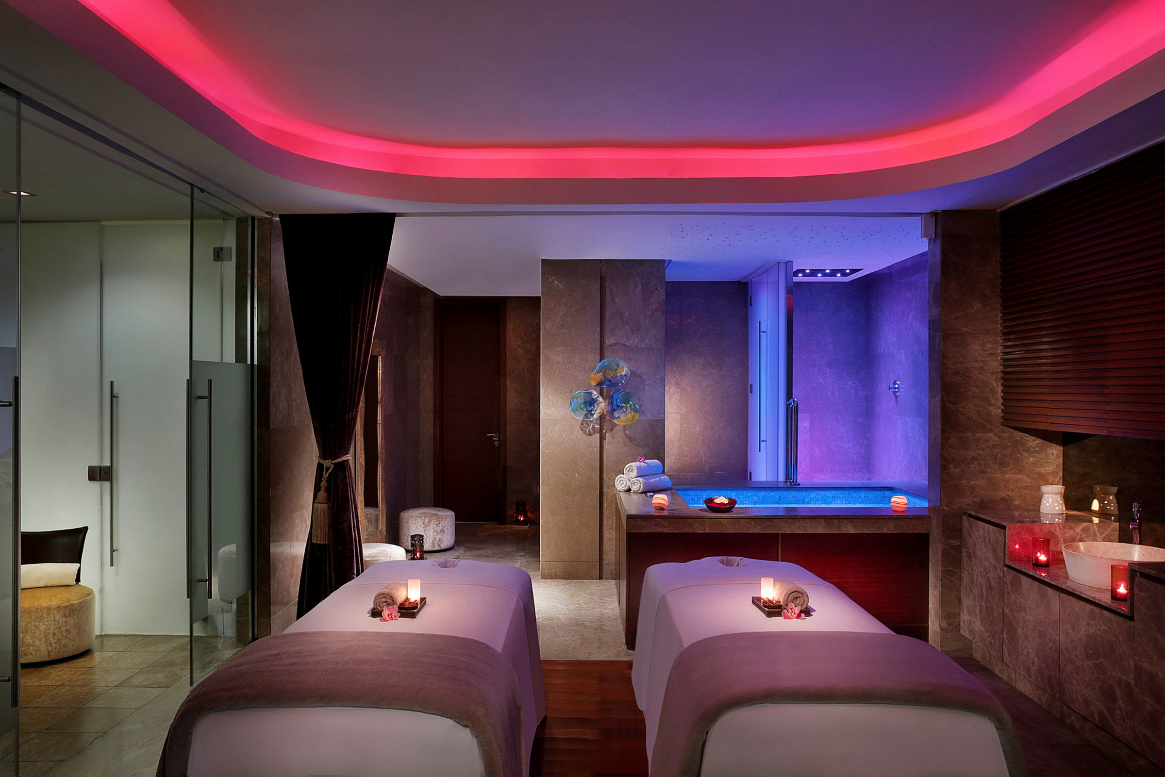 Et elegant spa-rum med to massageborde og et oplyst poolområde i baggrunden. (AI-genereret tekst)