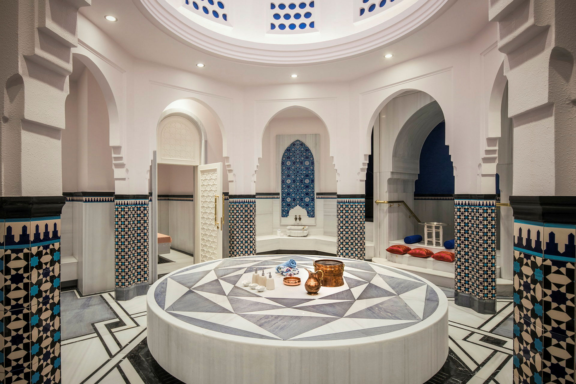 Et elegant tyrkisk hamam med en central keramisk platform og dekorative vægmønstre. (AI-genereret tekst)