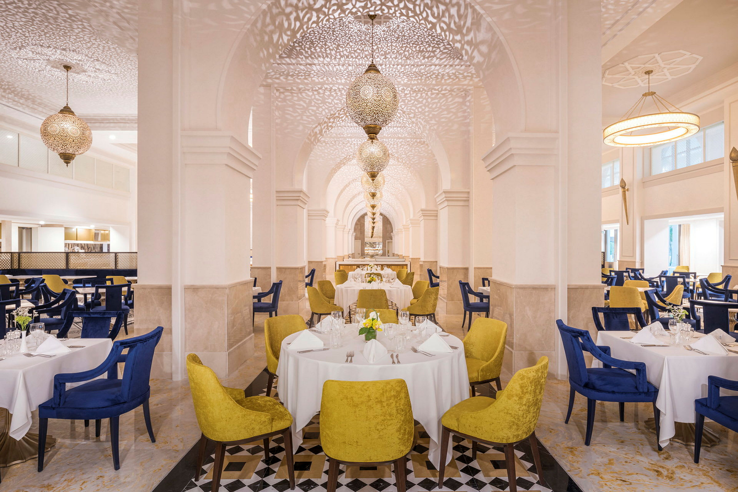 En elegant restaurant med hvide borde og stole i blå og gul farve. (AI-genereret tekst)