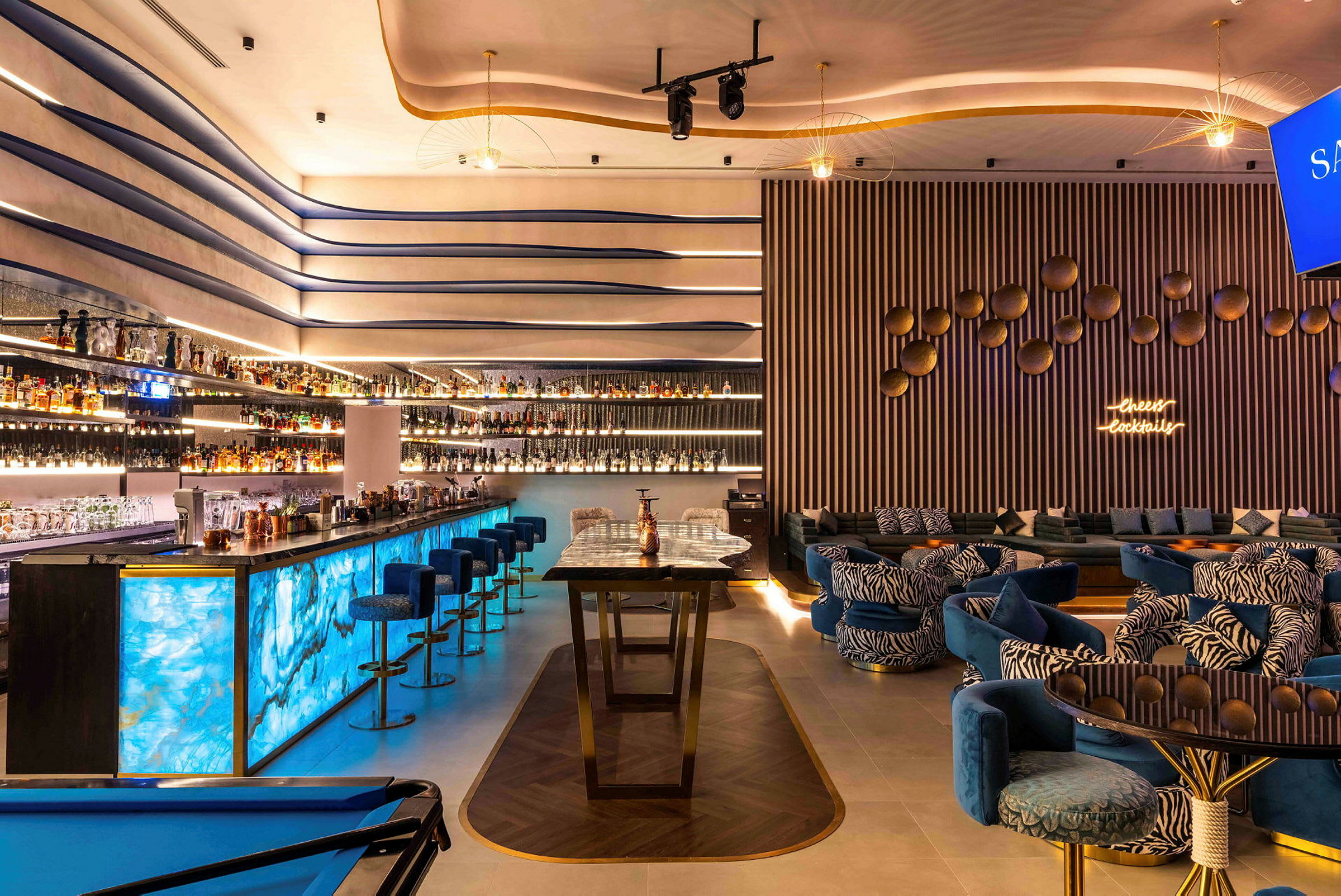 Moderne indrettet bar med blå belysning og loungeområde. (AI-genereret tekst)