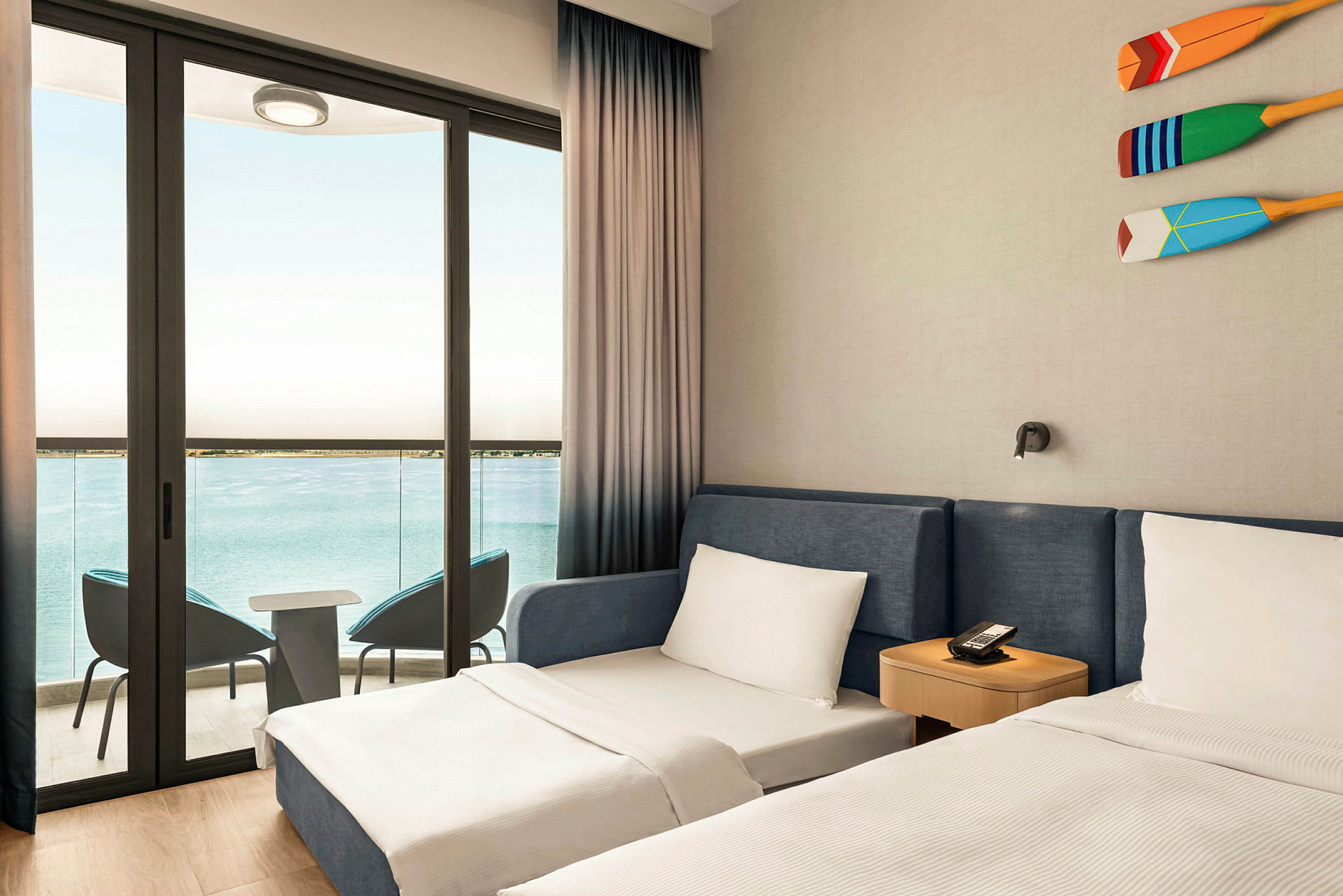 Et hotelværelse med to senge og en balkon med udsigt over havet. (AI-genereret tekst)