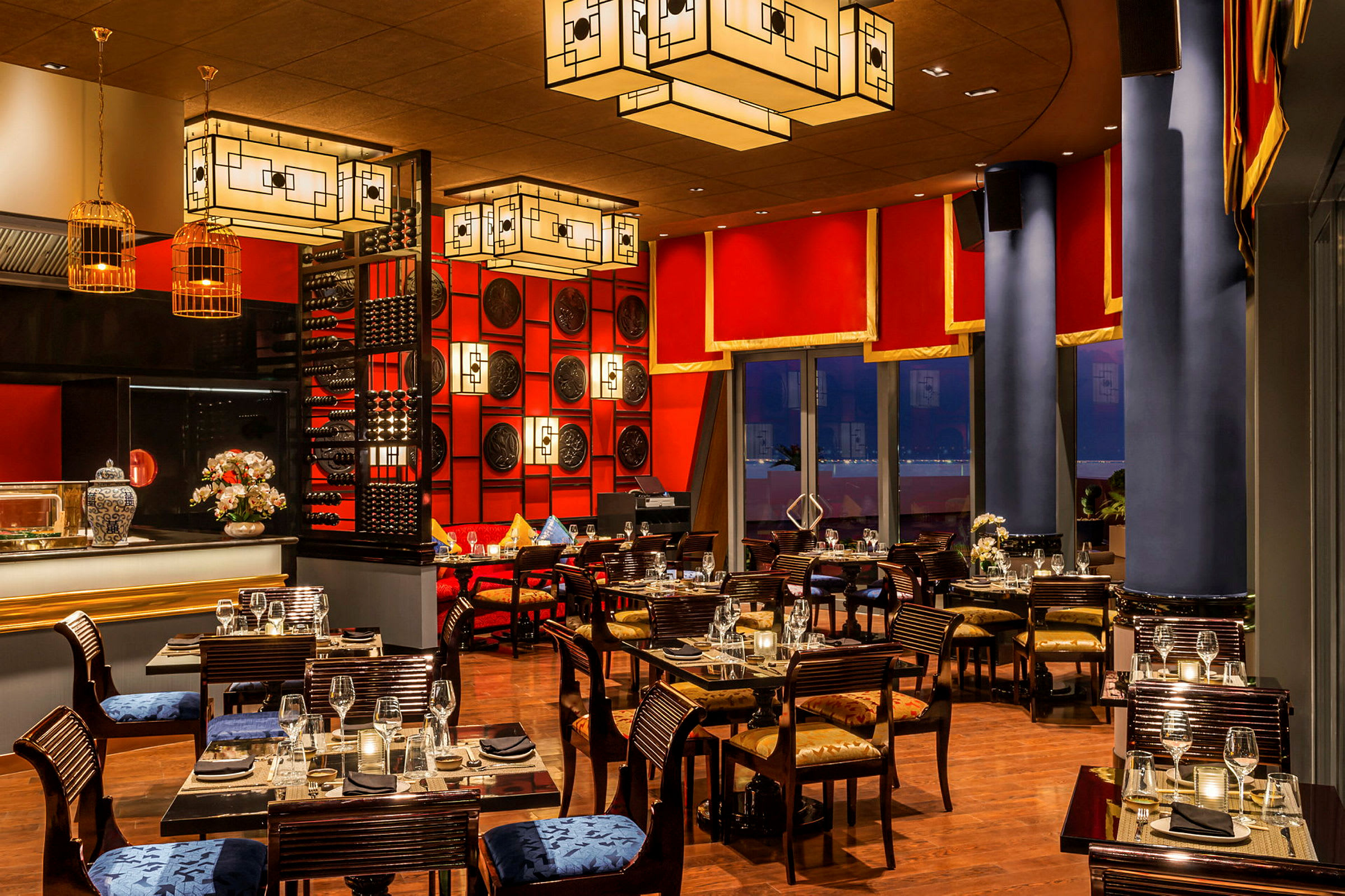 En elegant restaurant med røde og guldfarvede dekorationer, mørke møbler og smukt dækkede borde. (AI-genereret tekst)