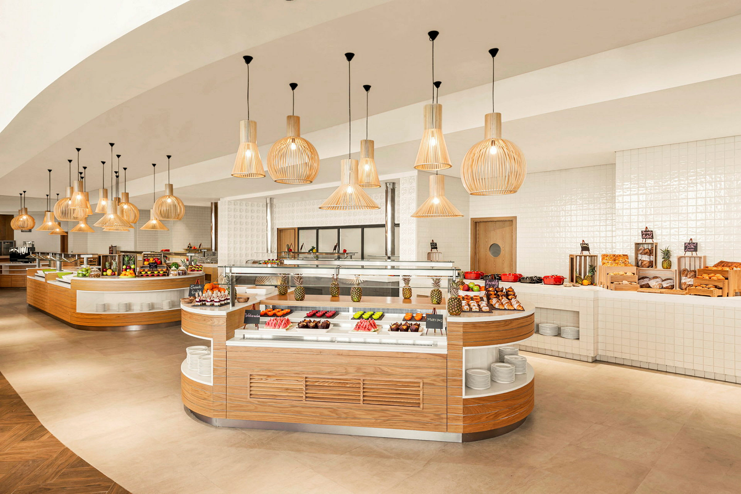 Et restaurantsbuffetområde med forskellige retter og frugt anrettet på borde under dekorative lamper. (AI-genereret tekst)