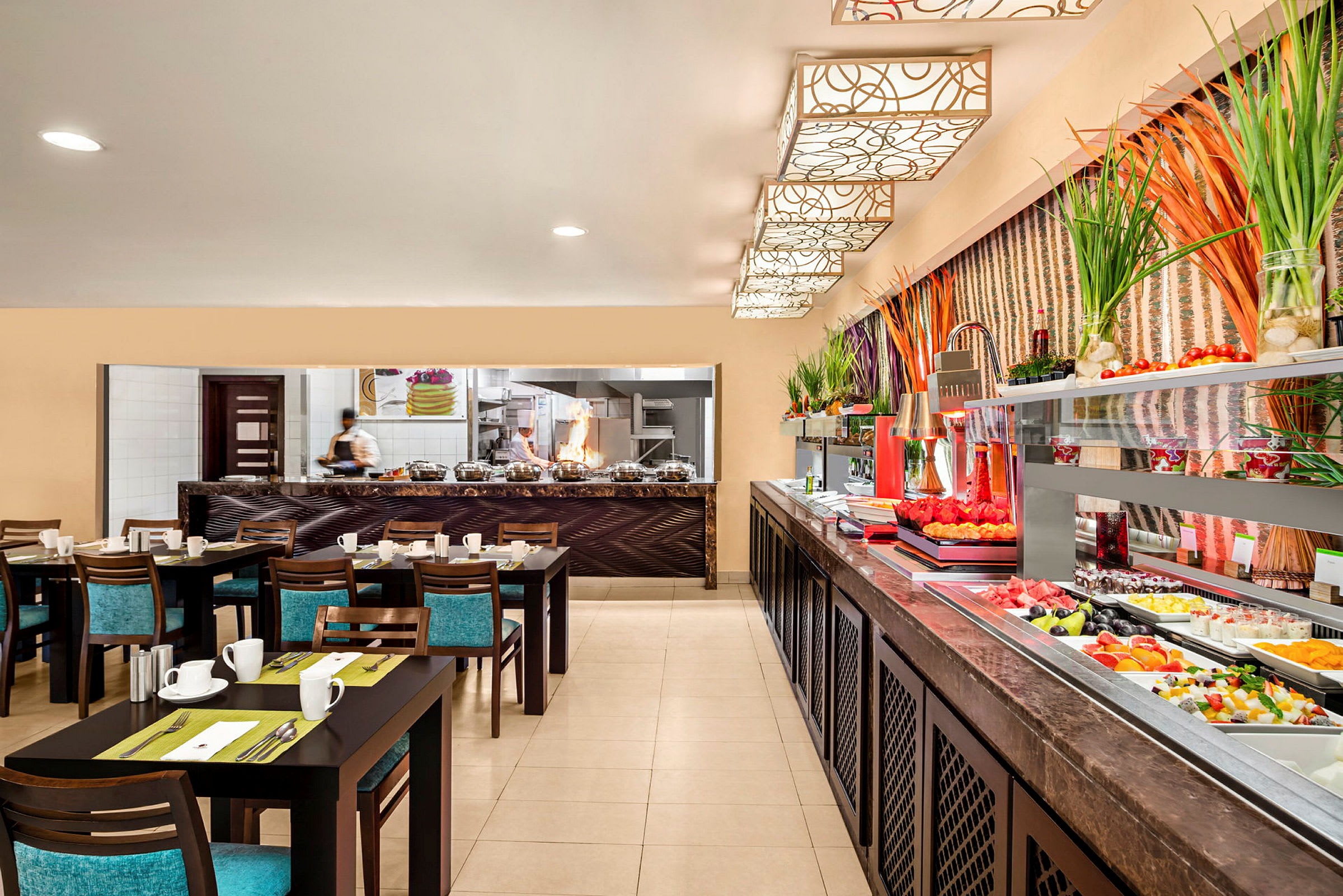Billede af et restaurantmiljø med dækkede borde, et åbent køkkenområde og en buffet med frisk frugt og grøntsager. (AI-genereret tekst)