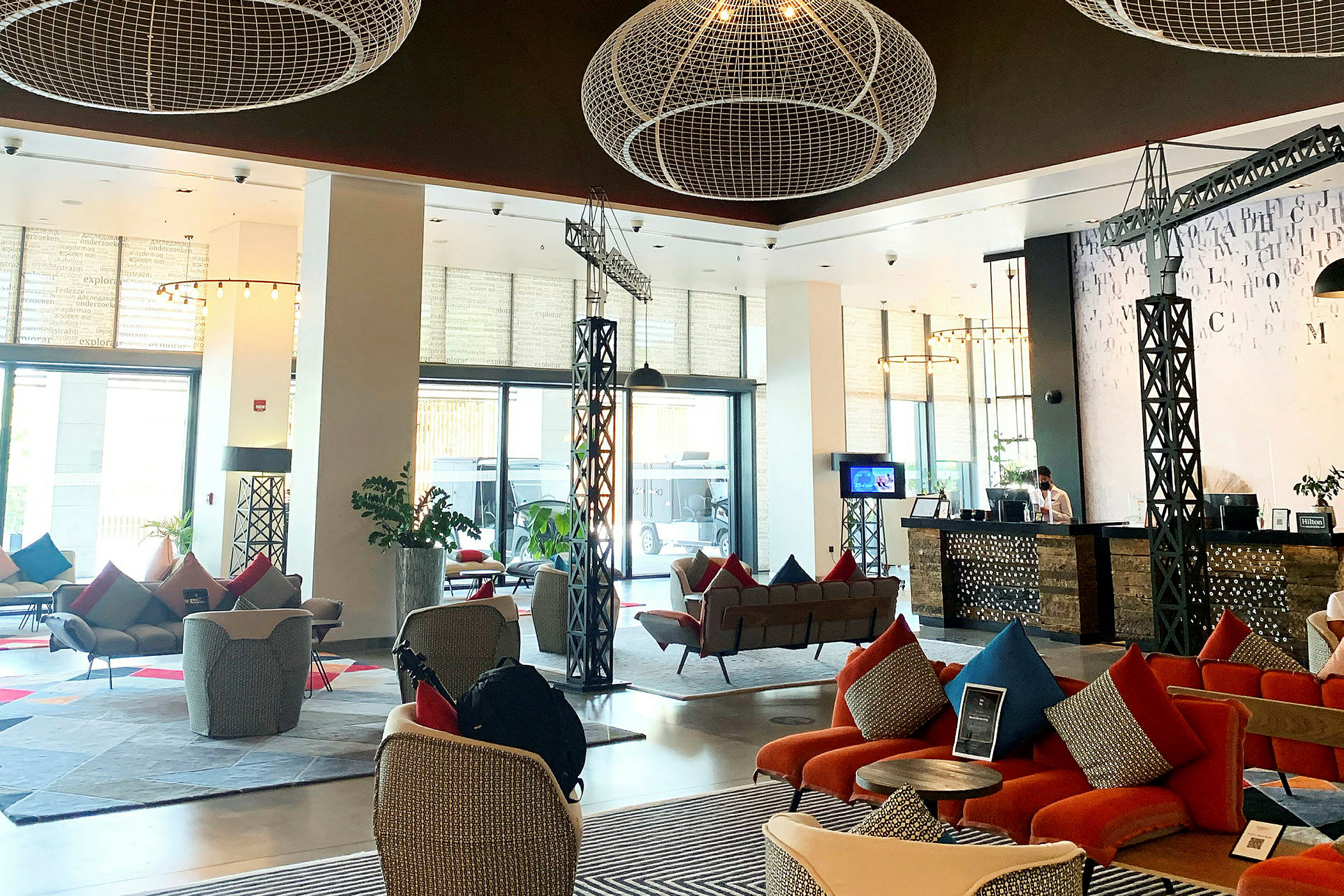 Lys og moderne hotellobby med siddegrupper, reception og dekorative elementer i loftet. (AI-genereret tekst)