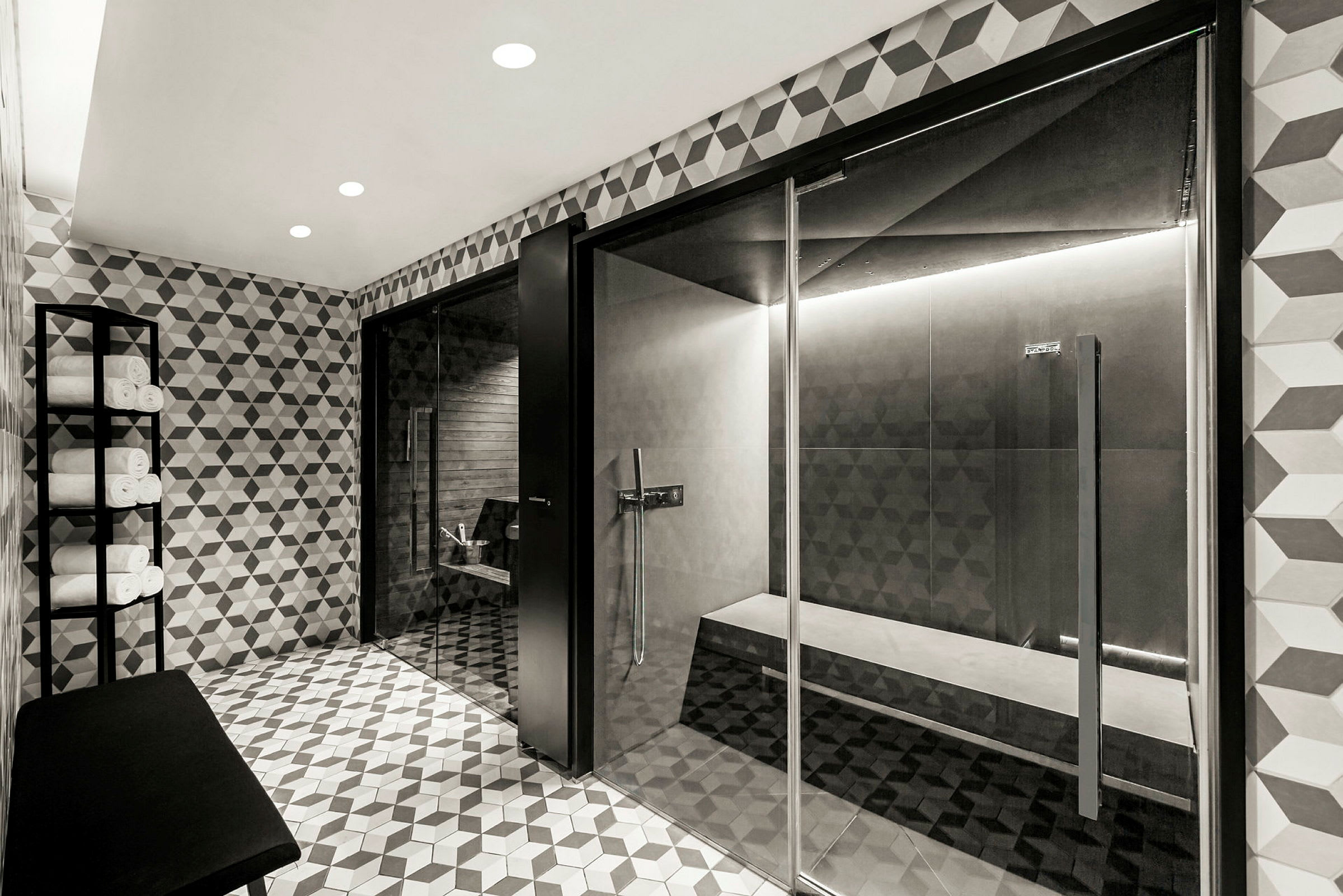 Et moderne spa med flisebelagt interiør, siddebænke og håndklæder placeret på en metalhylde. (AI-genereret tekst)
