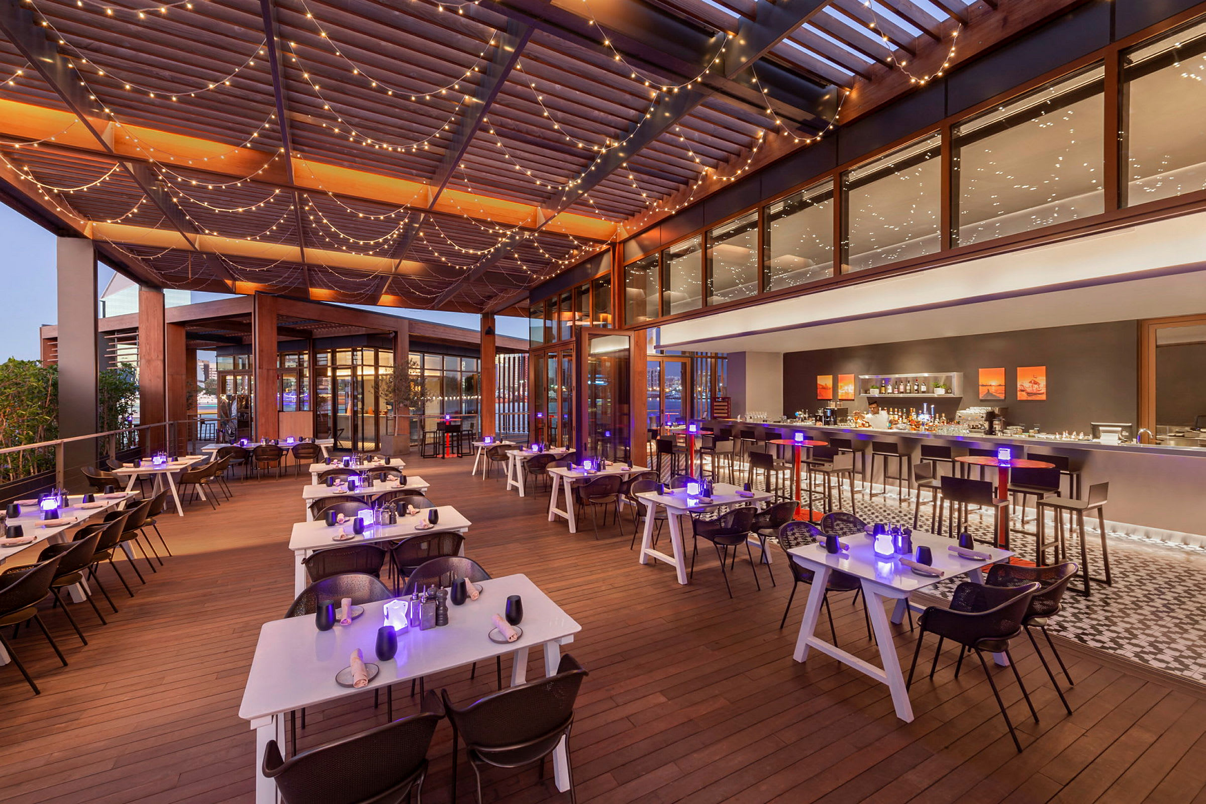En restaurantterrasse med dækkede borde og lyskæder i loftet. (AI-genereret tekst)