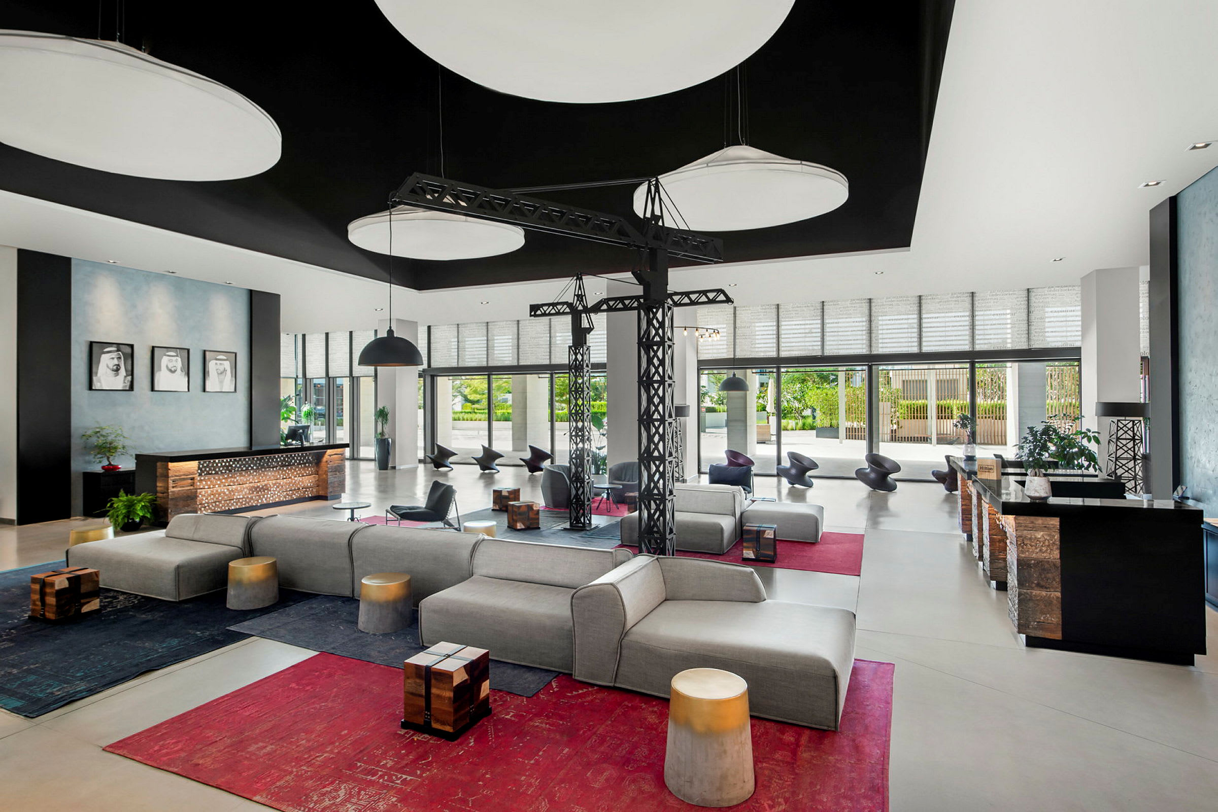 En moderne hotellobby med komfortable siddepladser, designbelysning og store vinduer, der lukker naturligt lys ind. (AI-genereret tekst)