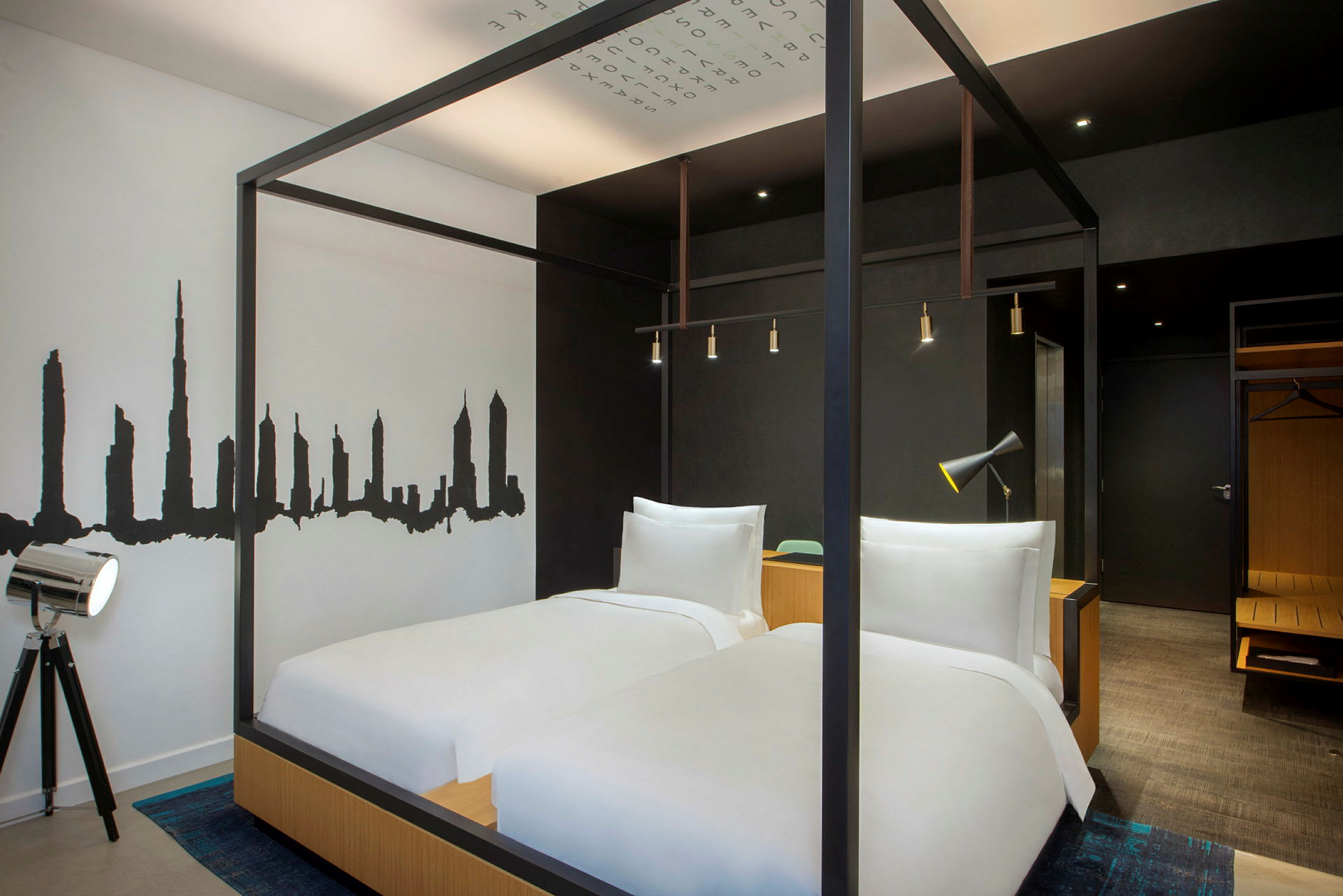Et moderne hotelværelse med to senge, sort-hvid vægdekoration og minimalistisk indretning. (AI-genereret tekst)