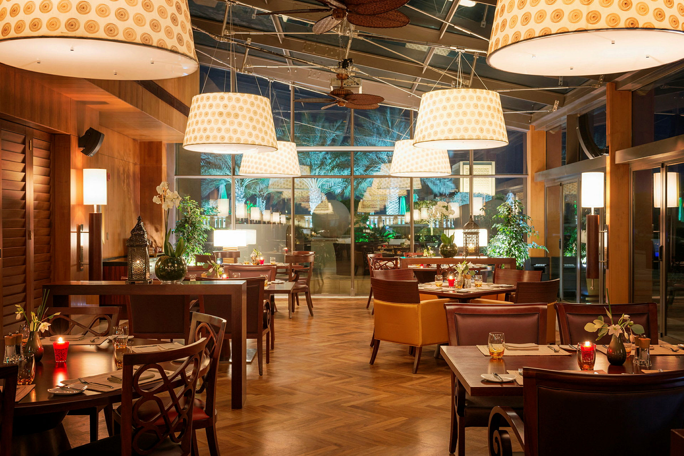 En restaurant med borde og stole, belysning og en glasvæg. (AI-genereret tekst)