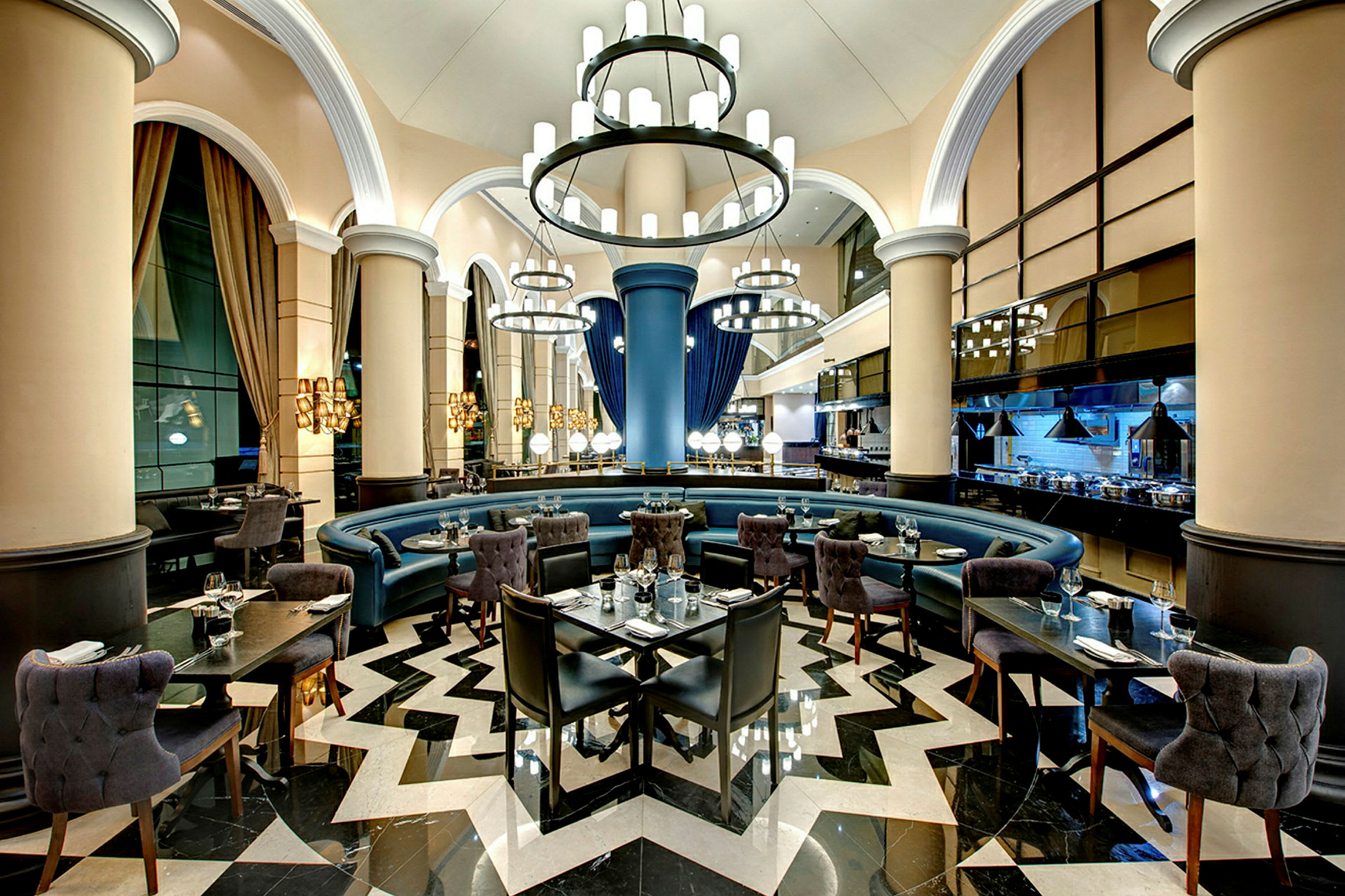 En elegant restaurant med højt til loftet, lysekroner, rund siddegruppe og moderne møbler. (AI-genereret tekst)