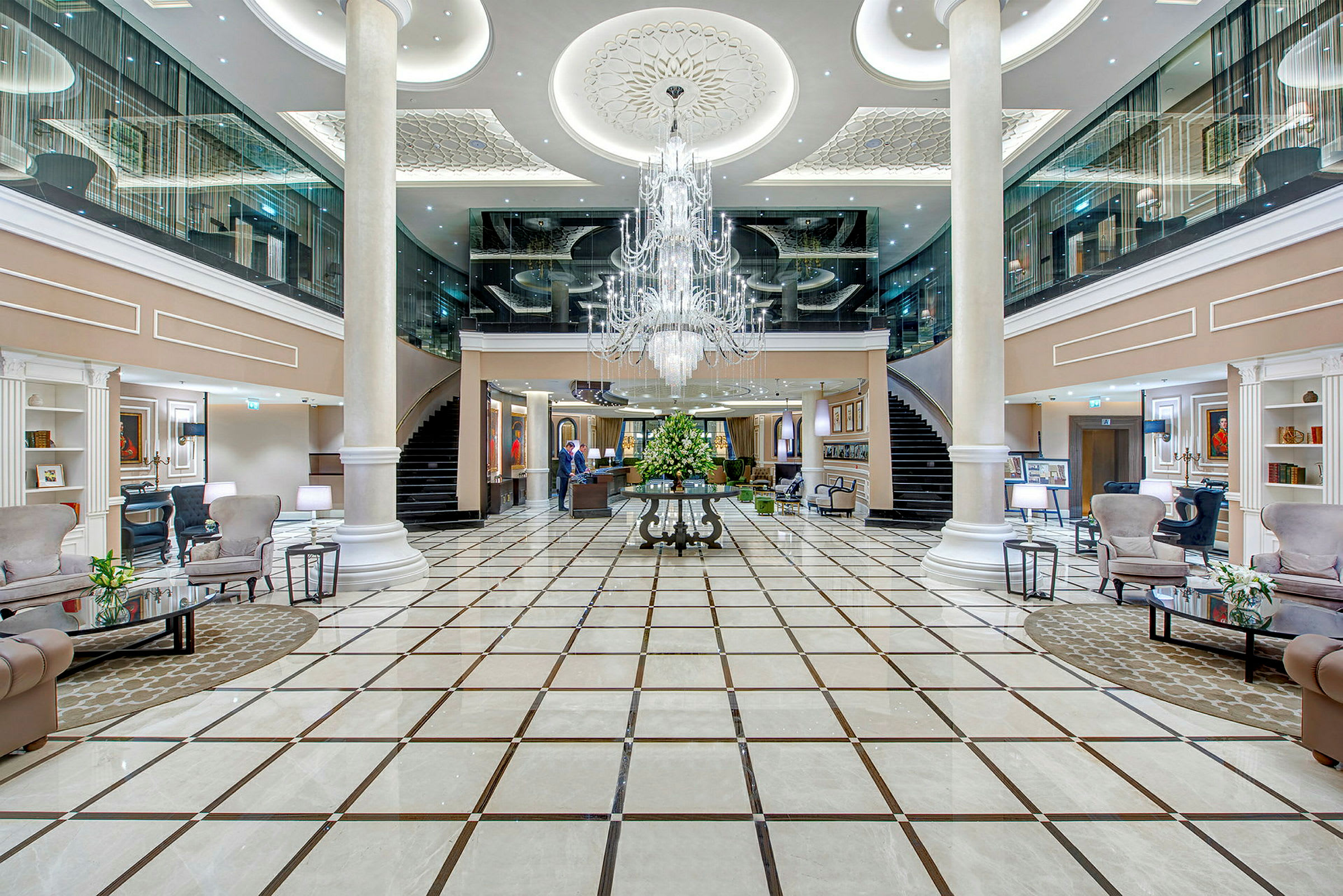Interiør af et elegant hotel med rummelig lobby, marmorgulv og centralt placeret lysekrone. (AI-genereret tekst)