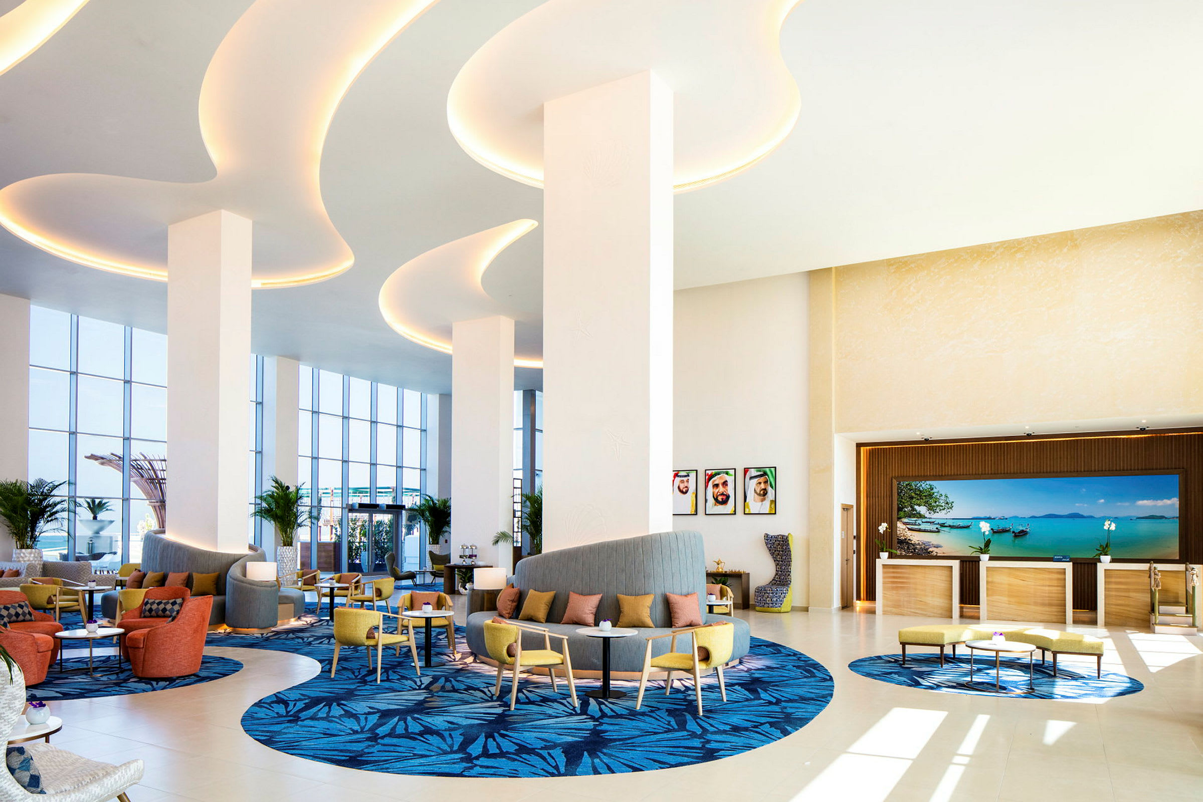 Lobbyen på et hotel med siddepladser, dekorative tæpper og store vinduer, der lader naturligt lys komme ind. (AI-genereret tekst)