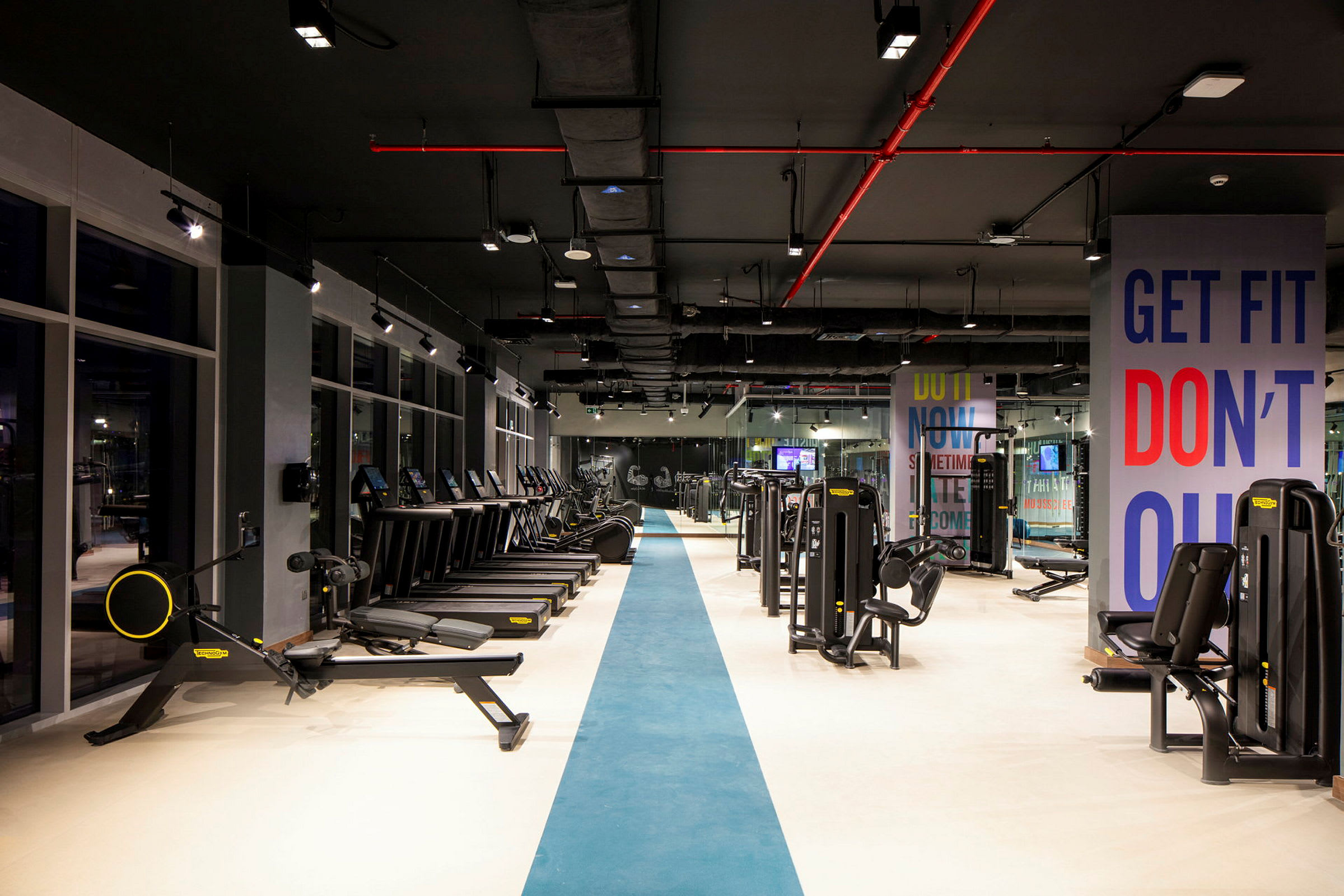 Et moderne fitnesscenter med forskellige træningsmaskiner og løbebånd. (AI-genereret tekst)