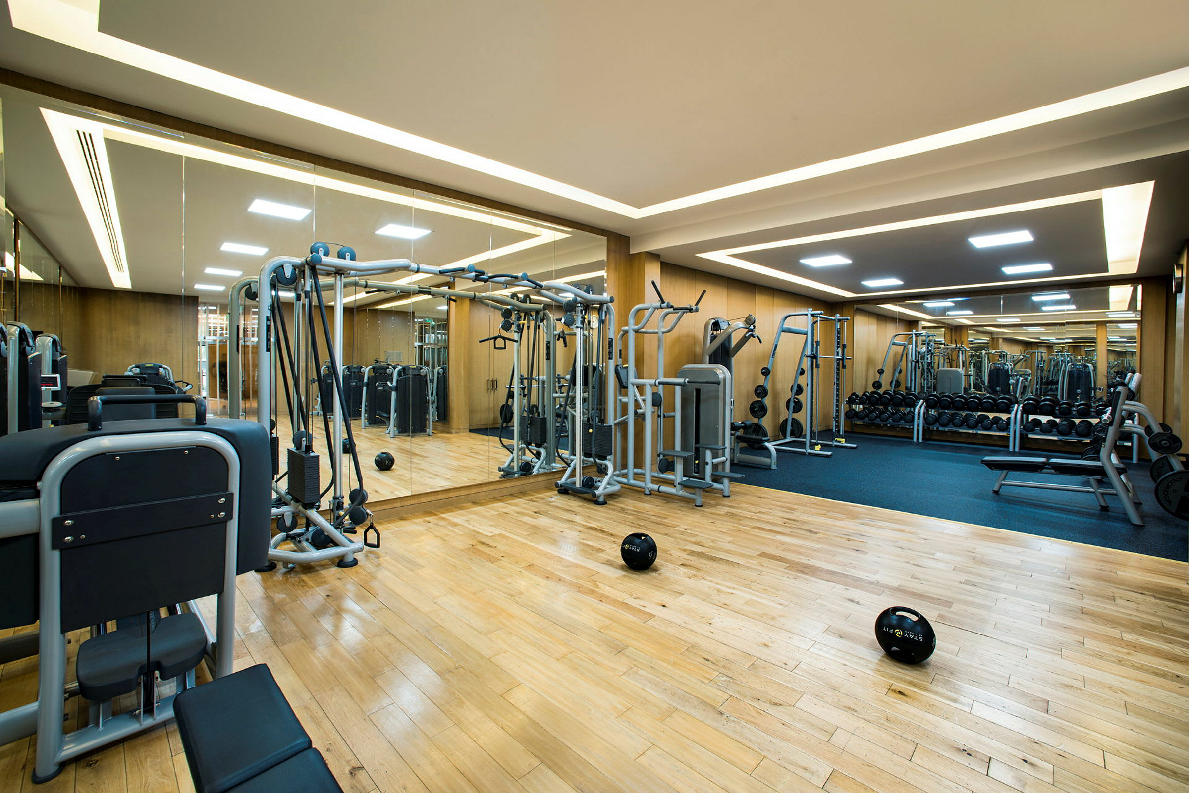 Fitnesscenter med træningsudstyr og spejlvægg. (AI-genereret tekst)
