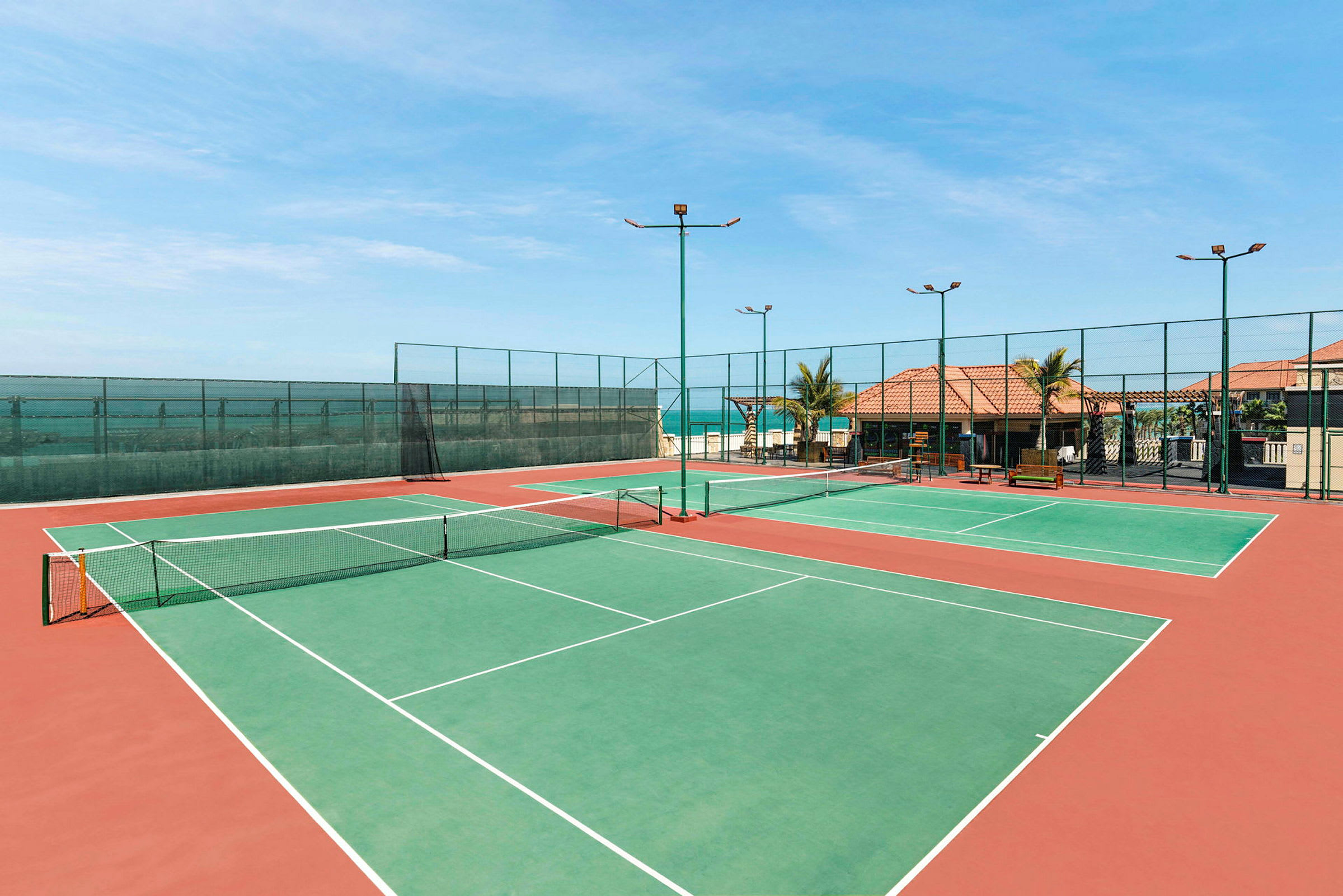 Billede af to tomme tennisbaner ved havet. (AI-genereret tekst)
