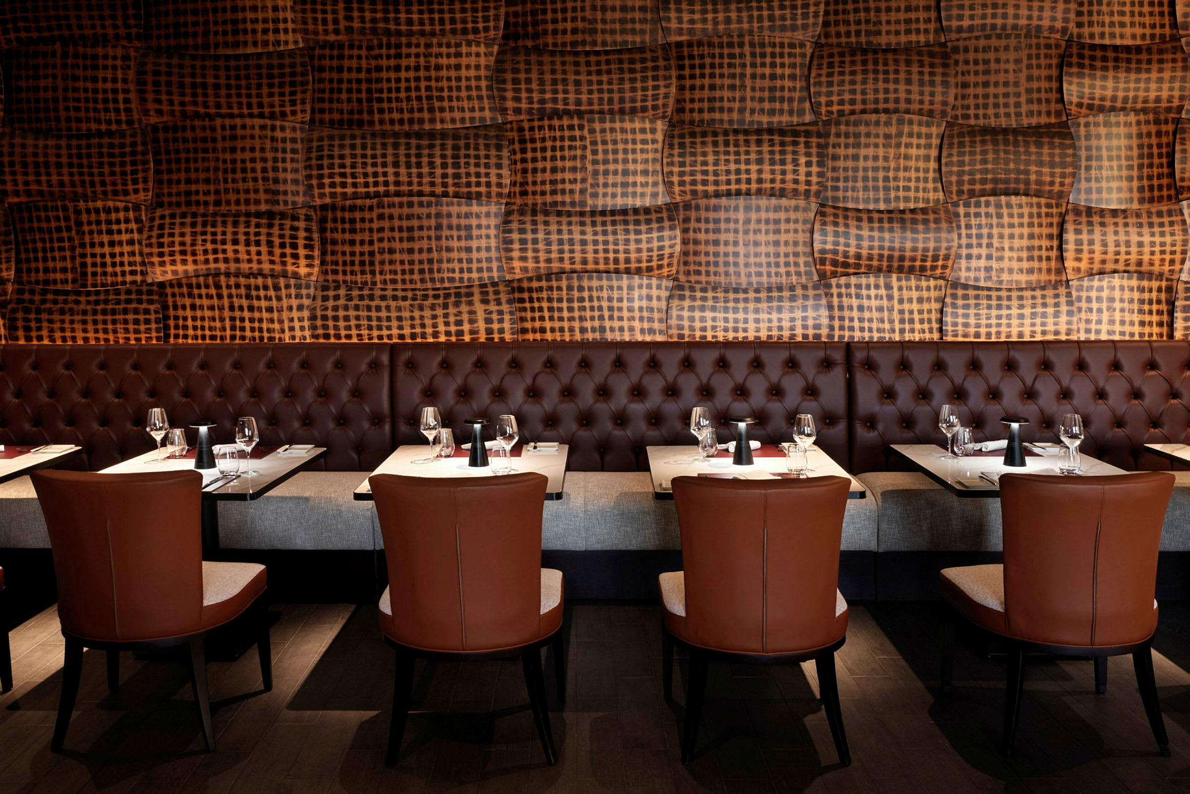 Et restaurantmiljø med sofaer, borde og stole samt en væg med et dekorativt mønster. (AI-genereret tekst)