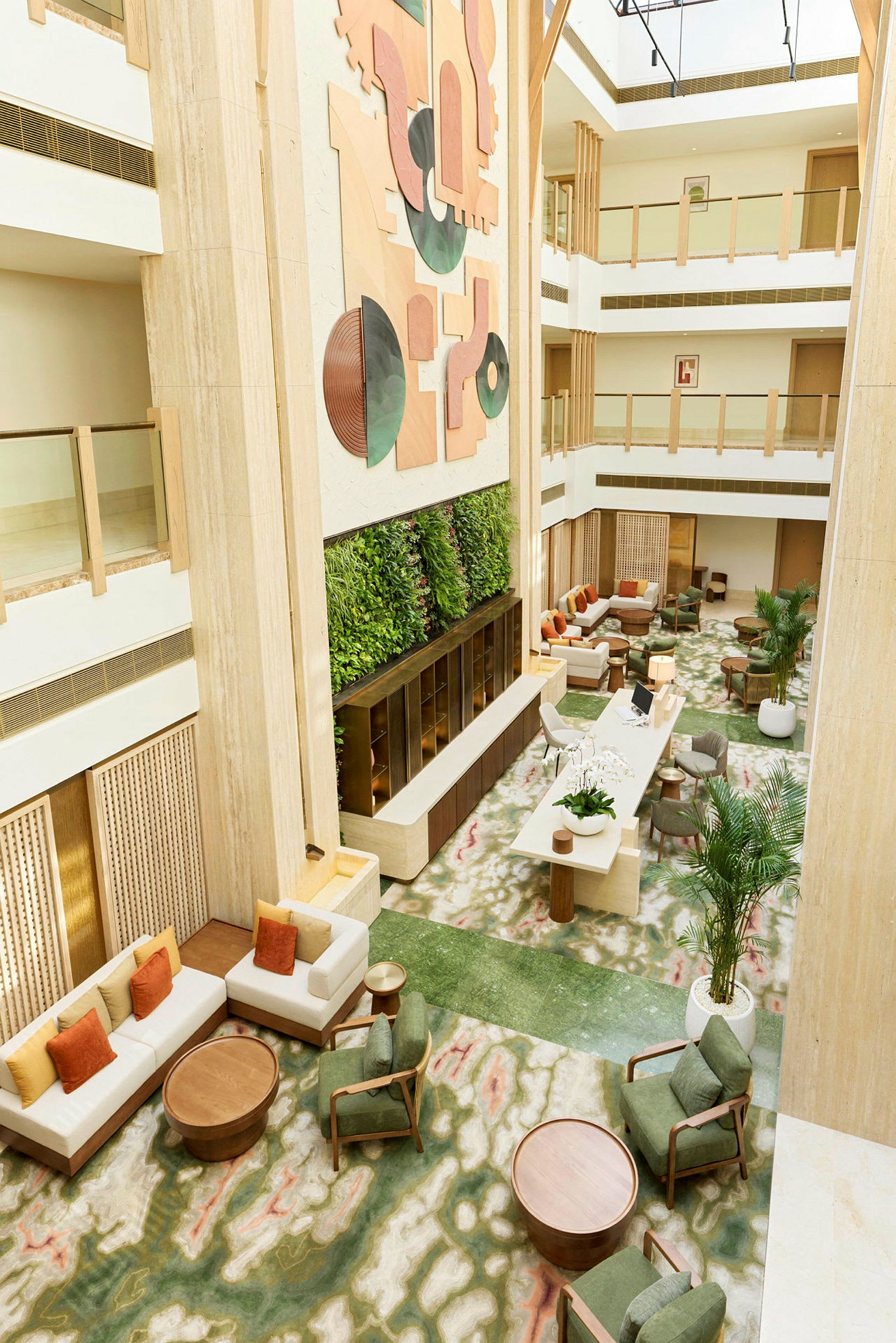 Hotellets foyer med siddegrupper, grøn plantevæg og moderne kunst på væggen. (AI-genereret tekst)