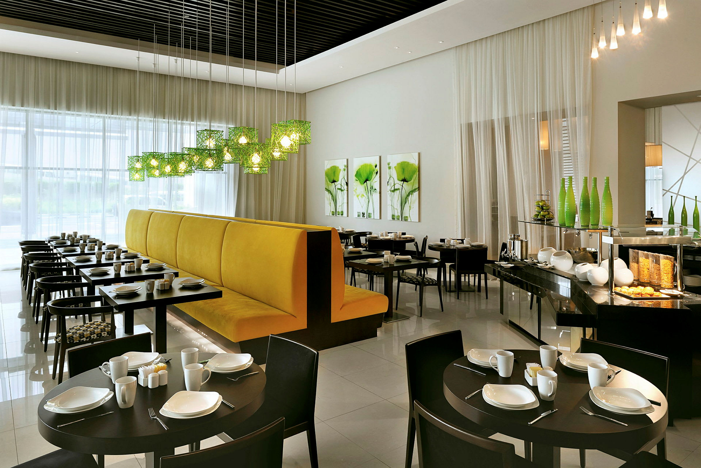 En moderne restaurant med dækkede borde og gul sofa ved et vindue. (AI-genereret tekst)