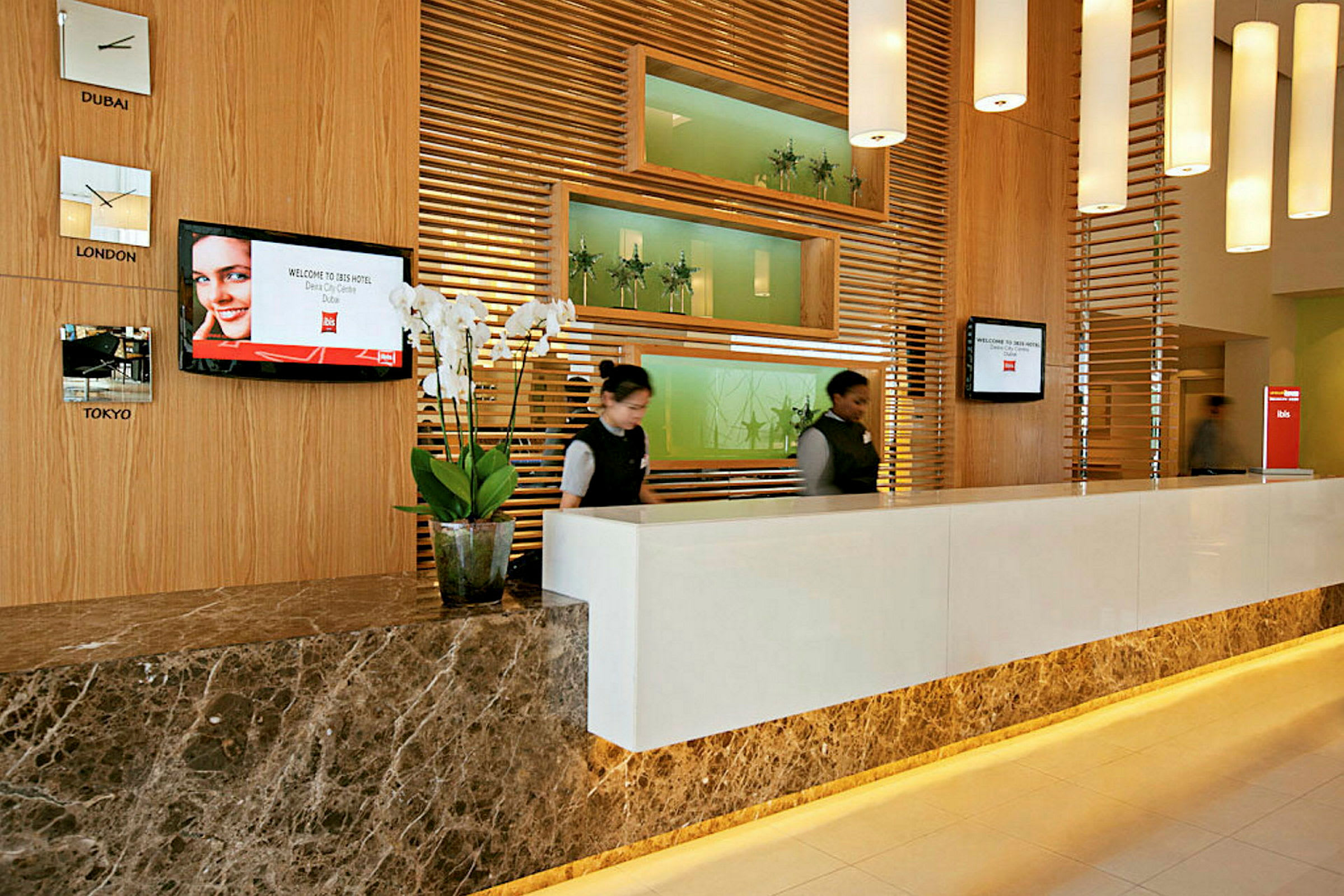 En receptionsskranke på et hotel med træpaneler, dekorative vægrelieffer og hvide væglamper. (AI-genereret tekst)