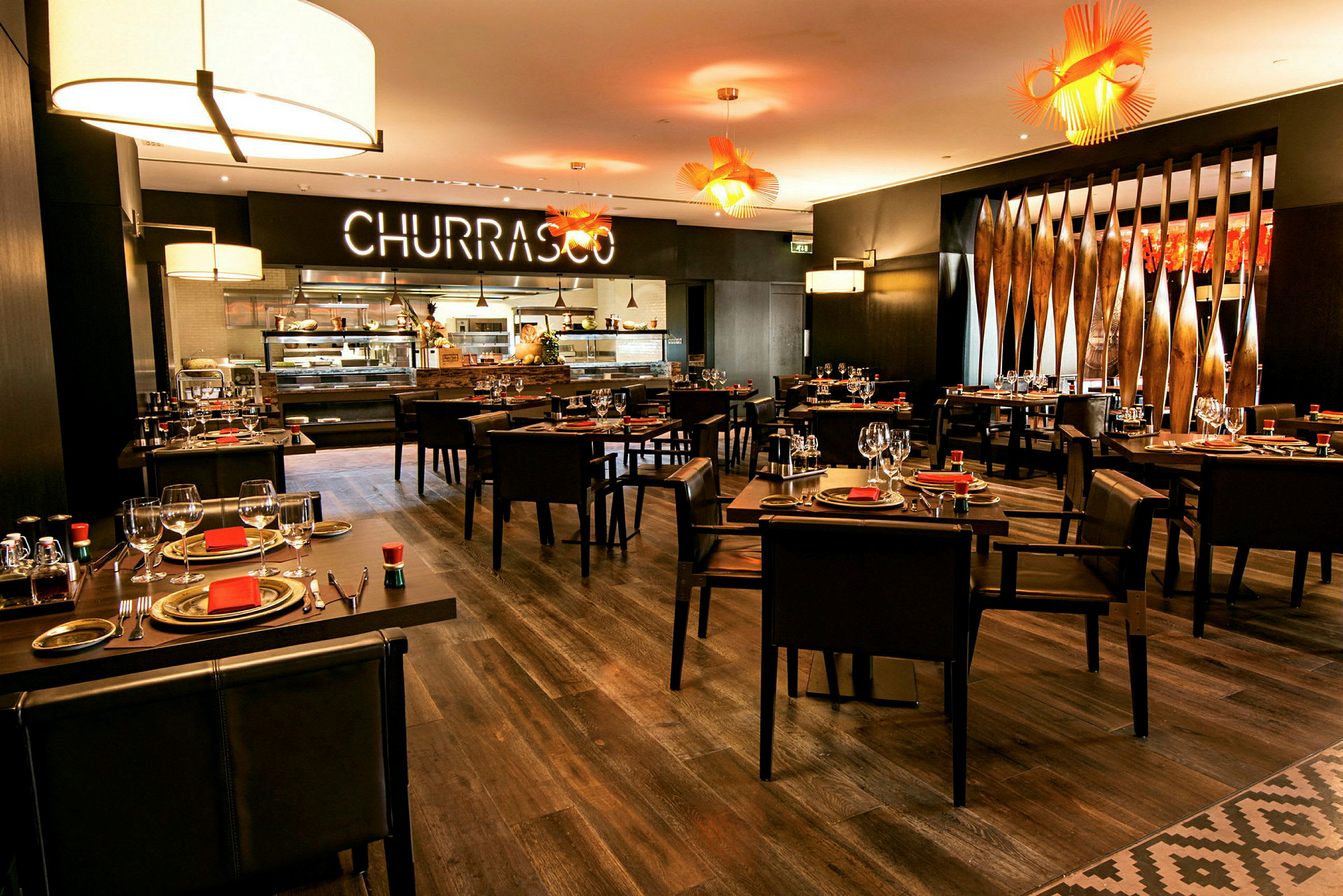 Restaurant med borde dækket med tallerkener og glas under moderne belysning. (AI-genereret tekst)