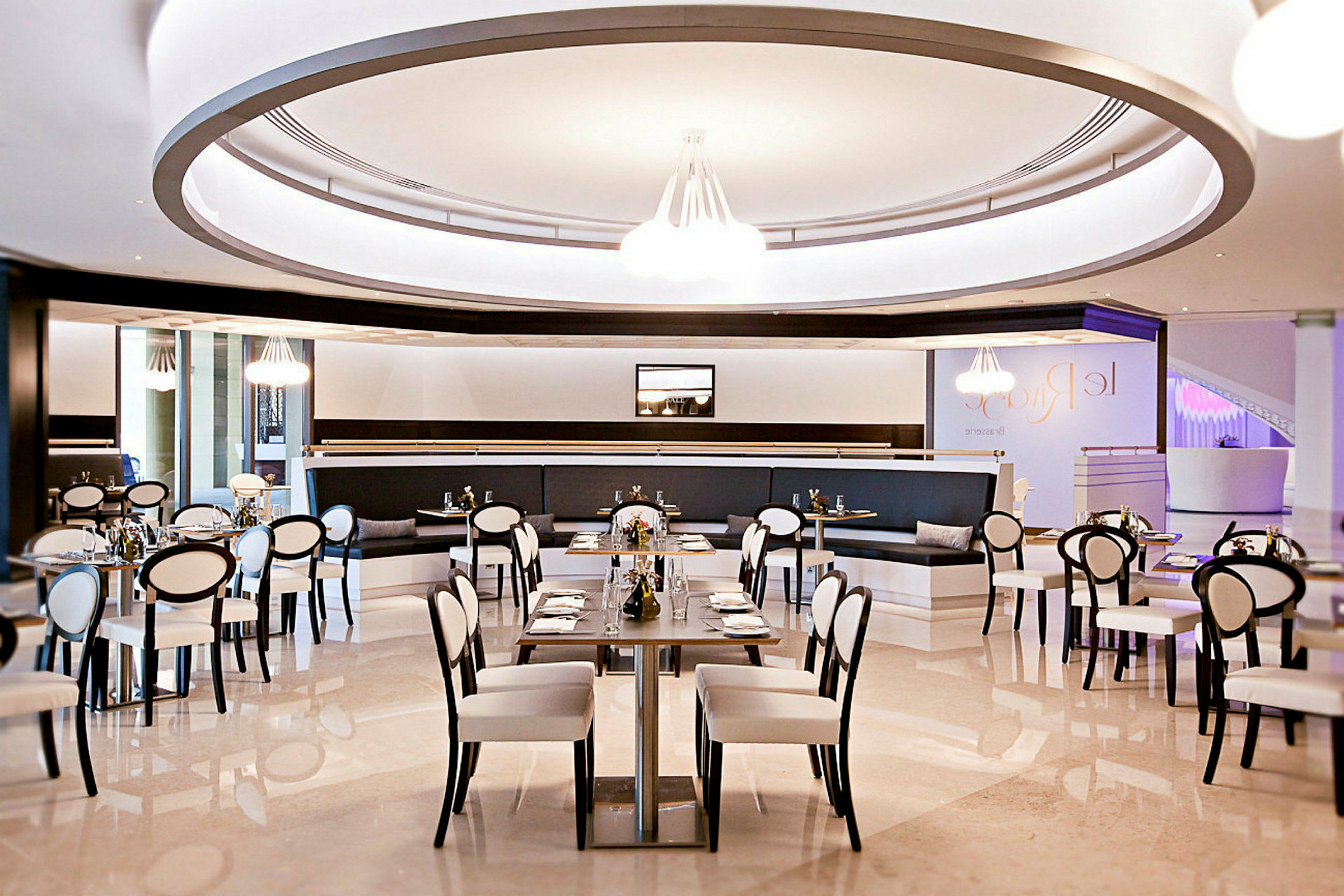 Billede af en moderne restaurant med stilfuld indretning, hvide stole med sorte rammer og dækkede borde. (AI-genereret tekst)