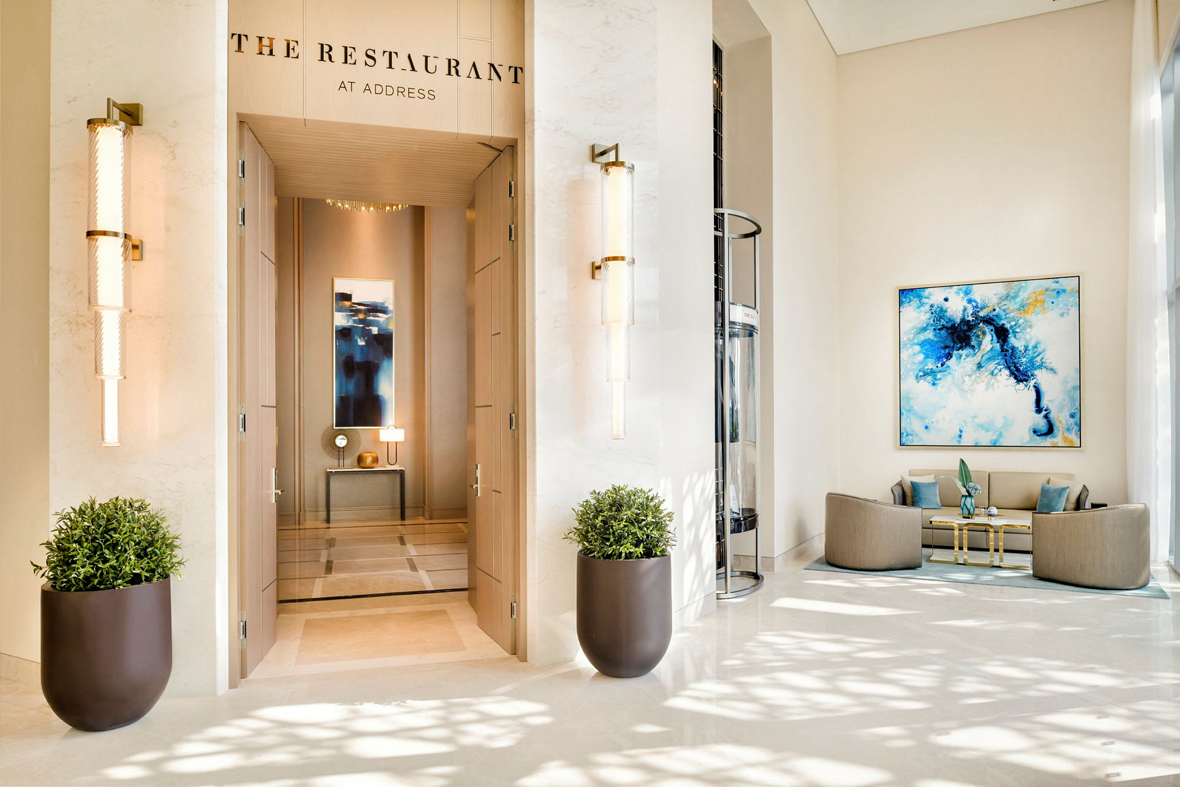 En elegant hotellobby med indgangen til "The Restaurant" synlig, to store blomsterkrukker og en siddegruppe til højre. (AI-genereret tekst)