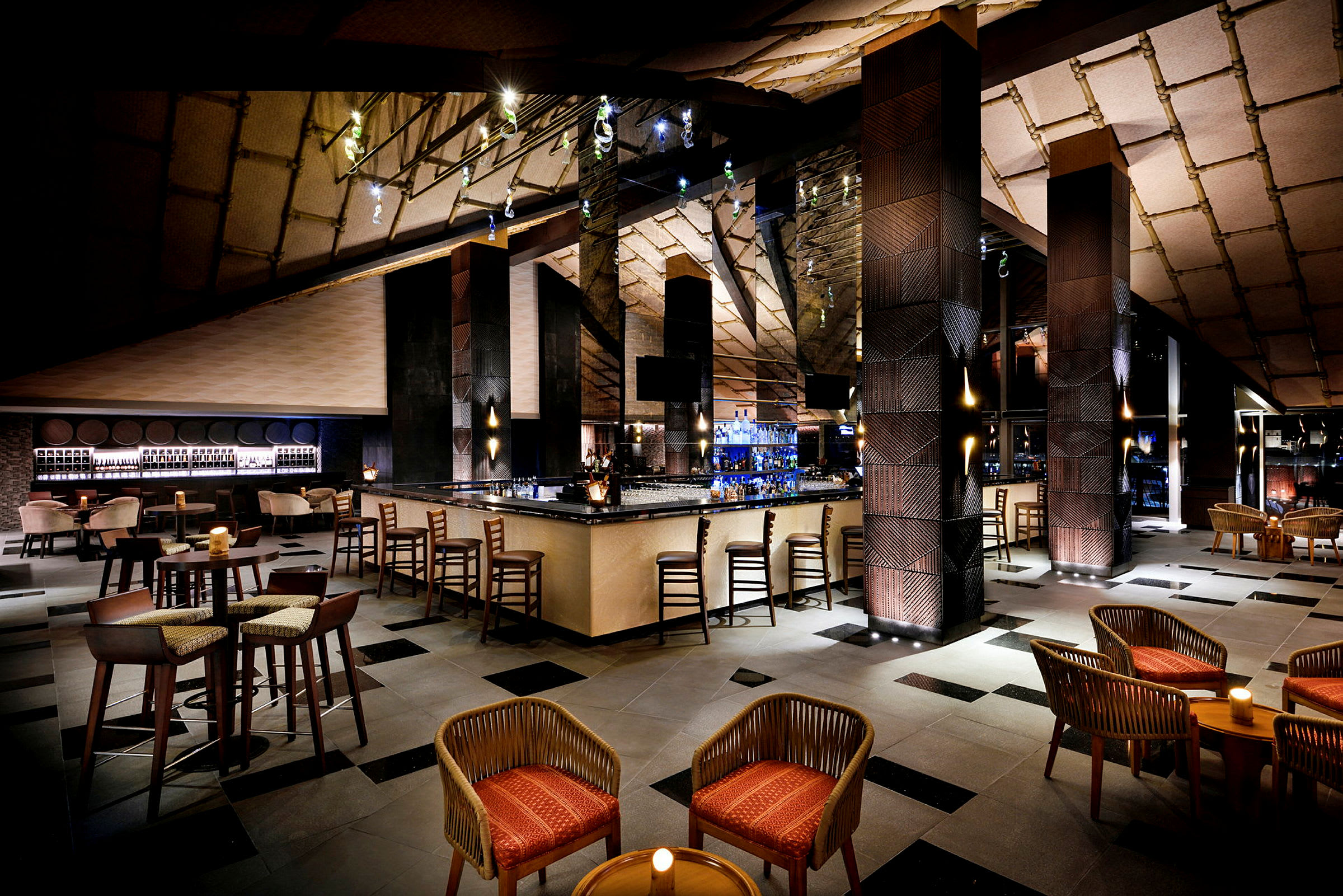 En elegant lounge med en central bardisk, siddegrupper med stole og borde samt stemningsfuld belysning. (AI-genereret tekst)