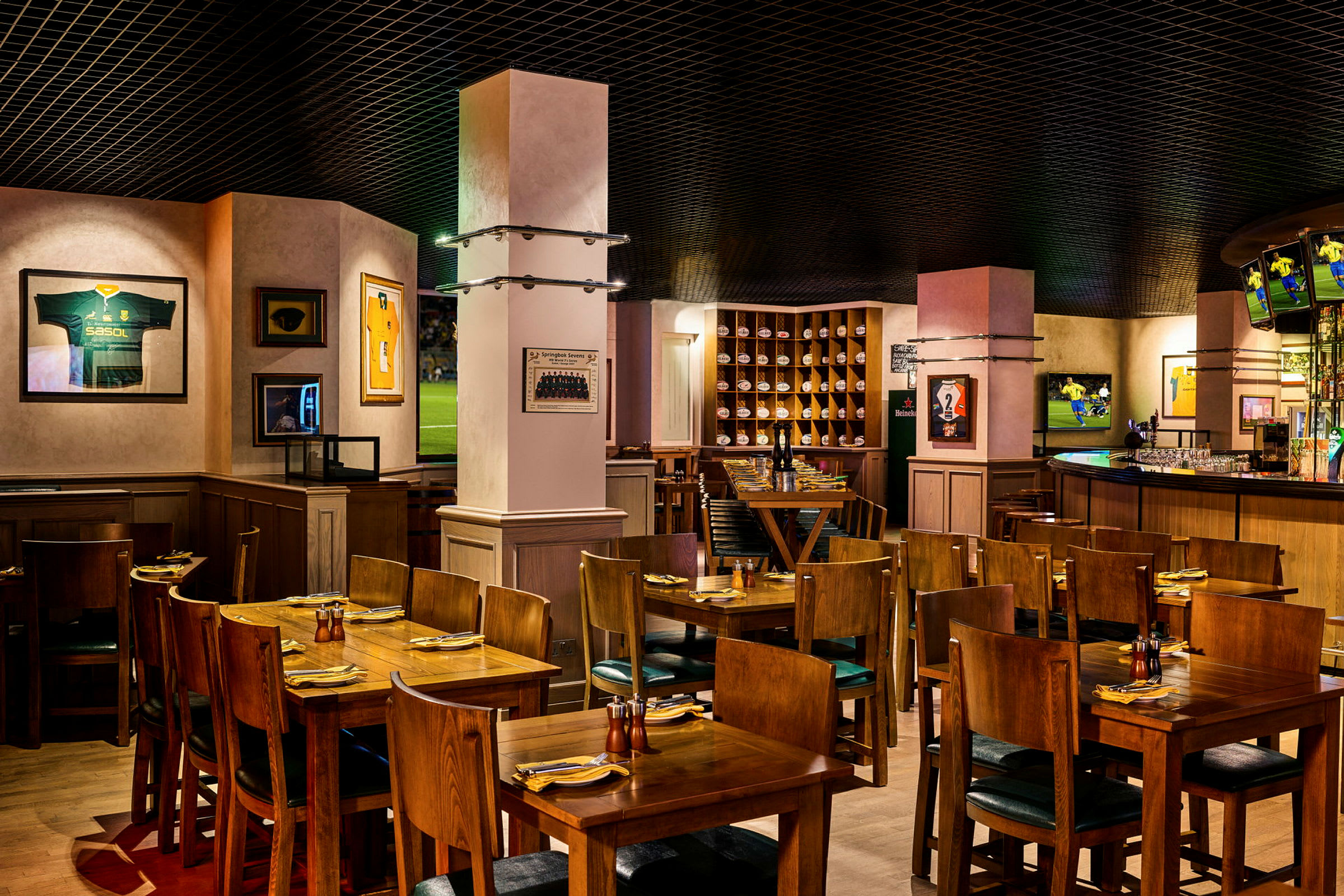 En restaurantinteriør med træborde og stole, dekoreret med sportsmemorabilia på væggene. (AI-genereret tekst)