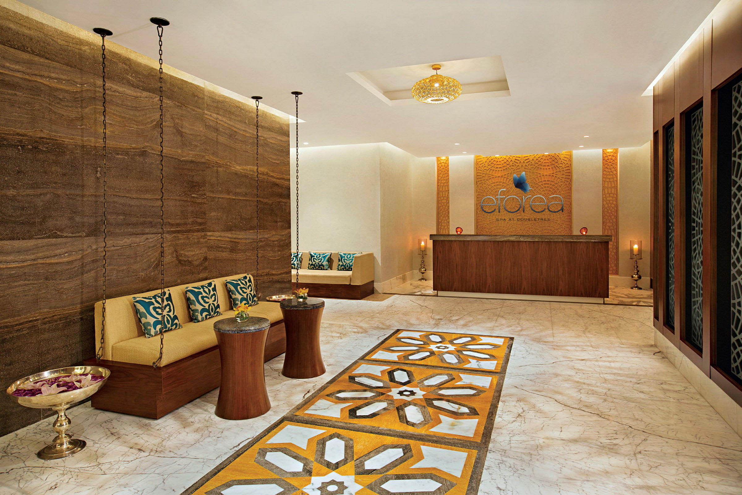 Interiør af en spa-lounge med marmorgulv, siddeområde og en receptionsskranke. (AI-genereret tekst)