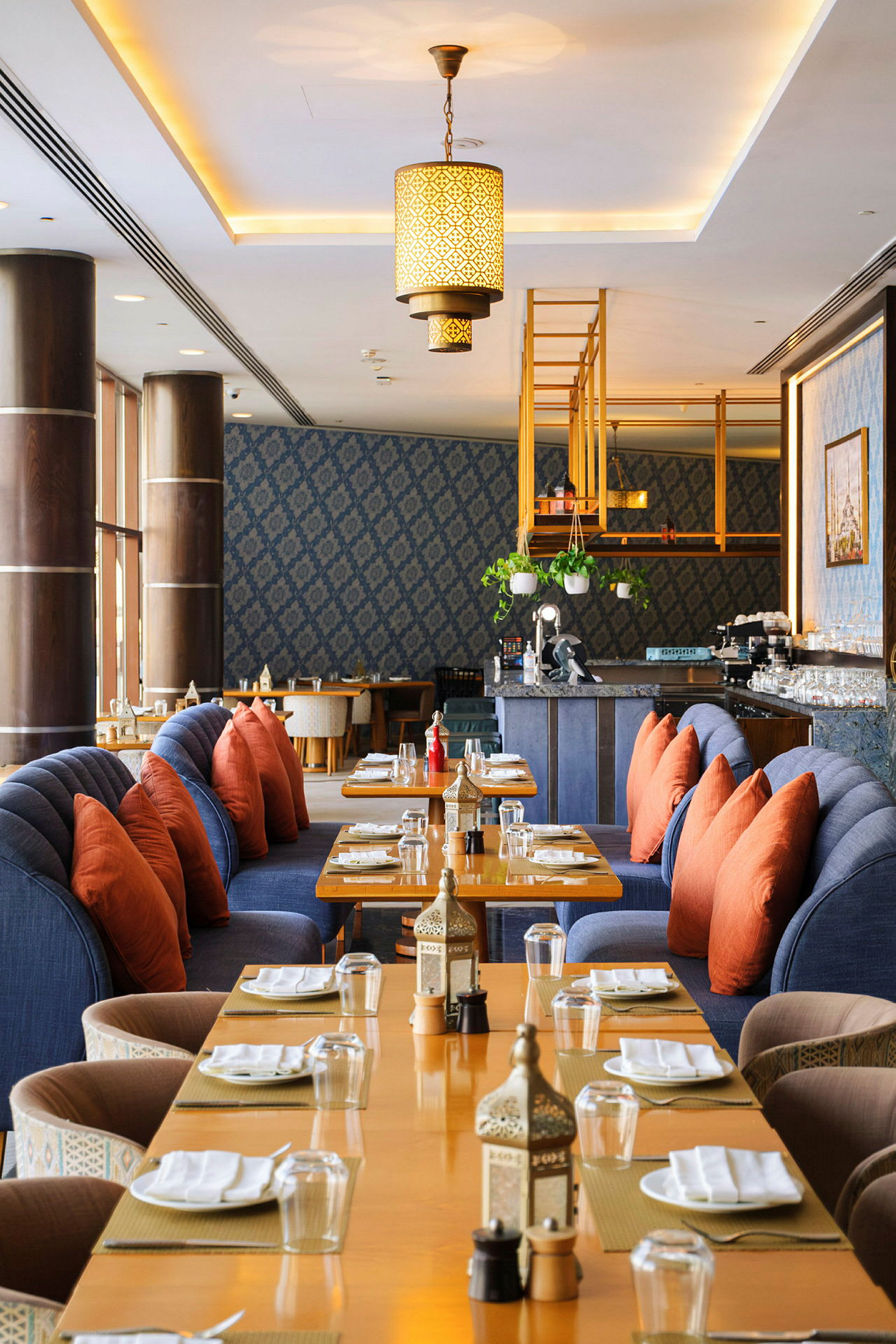 En restaurant med dækkede borde, blå sofaer og orange puder. (AI-genereret tekst)