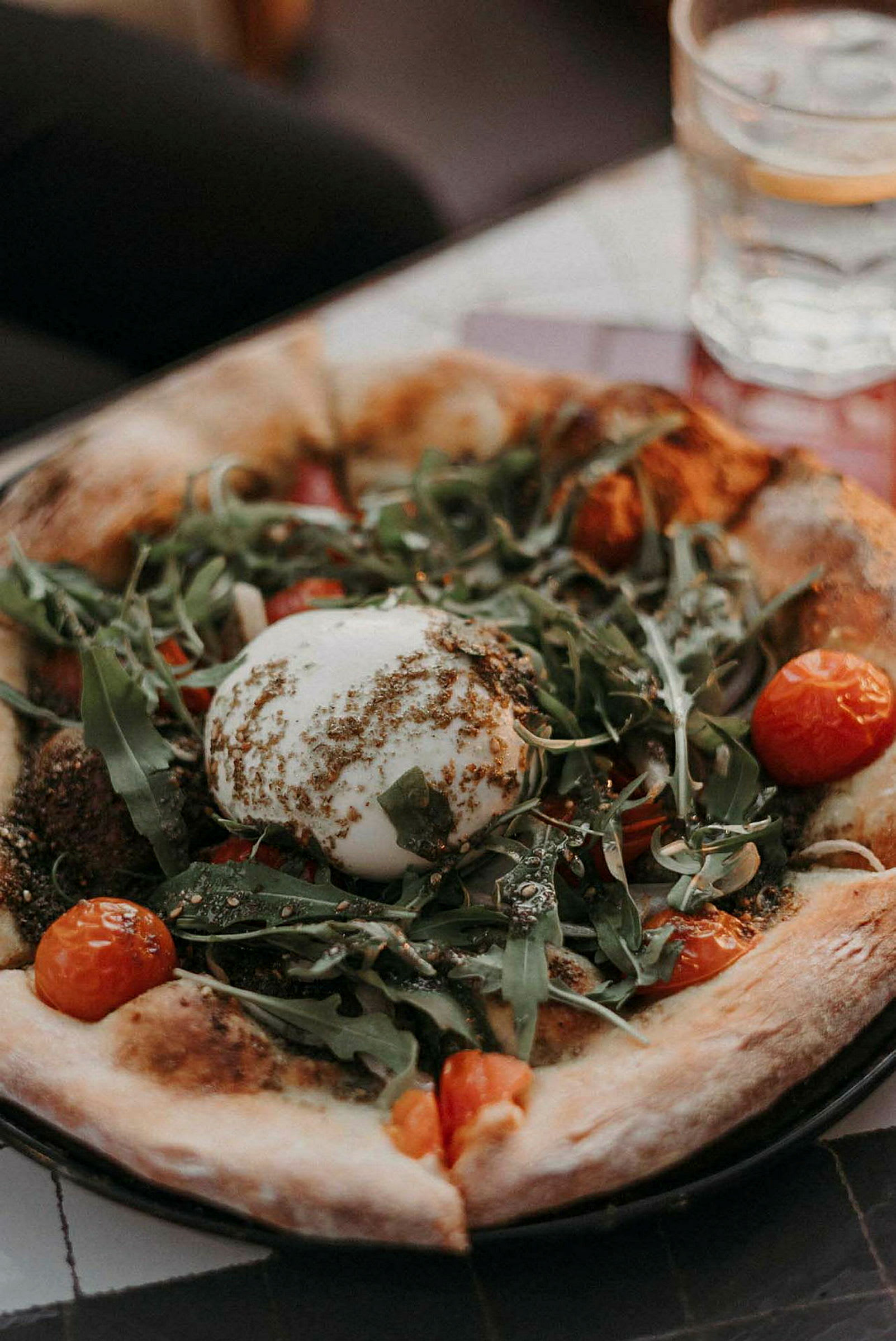 Pizza med burrataost, rucola og cherrytomater. (AI-genereret tekst)