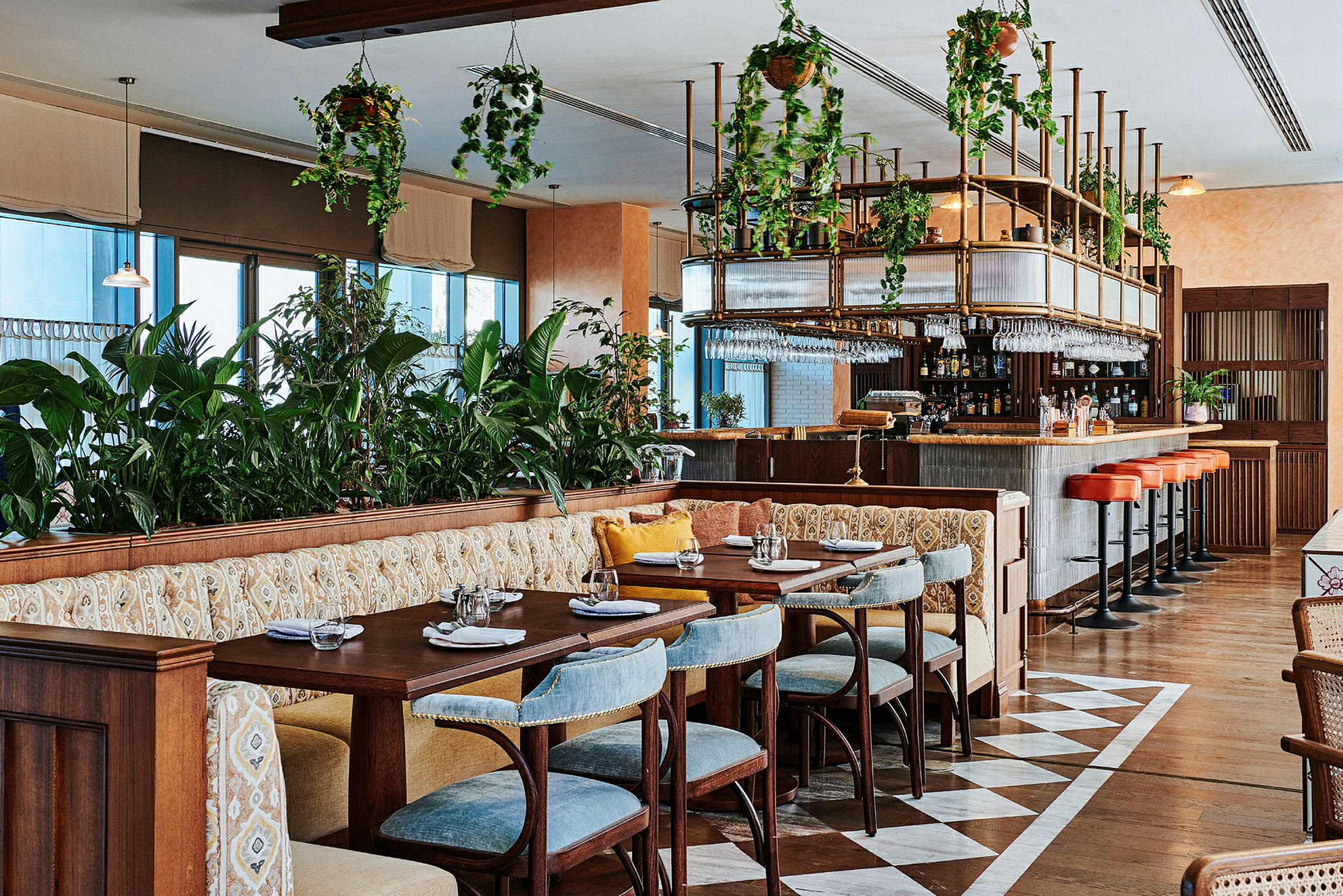 Restaurant med borde og stole, siddepladser og bar med hængende plantedekorationer. (AI-genereret tekst)