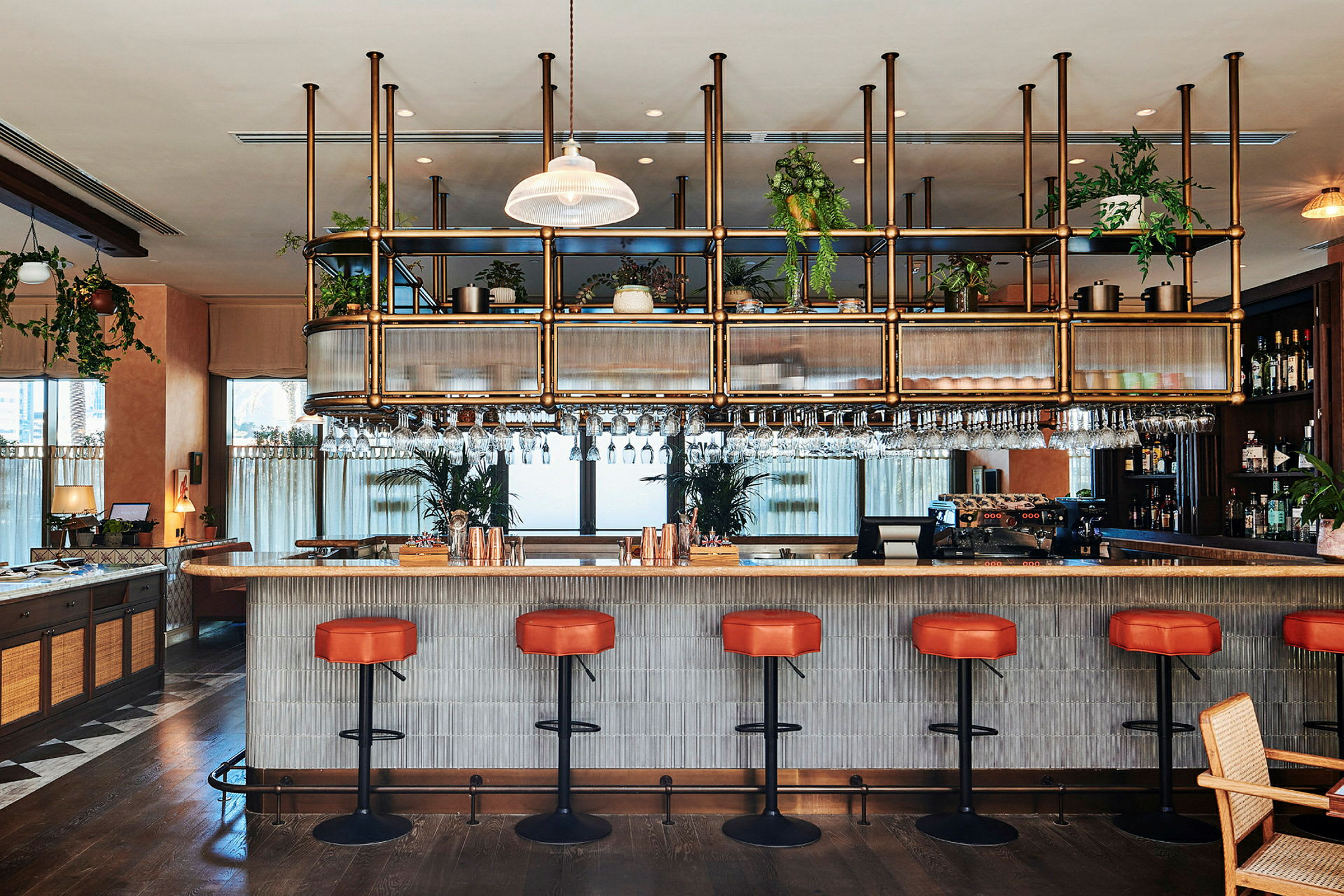 En moderne bar med røde stole og en bardisk med hængende glas. (AI-genereret tekst)